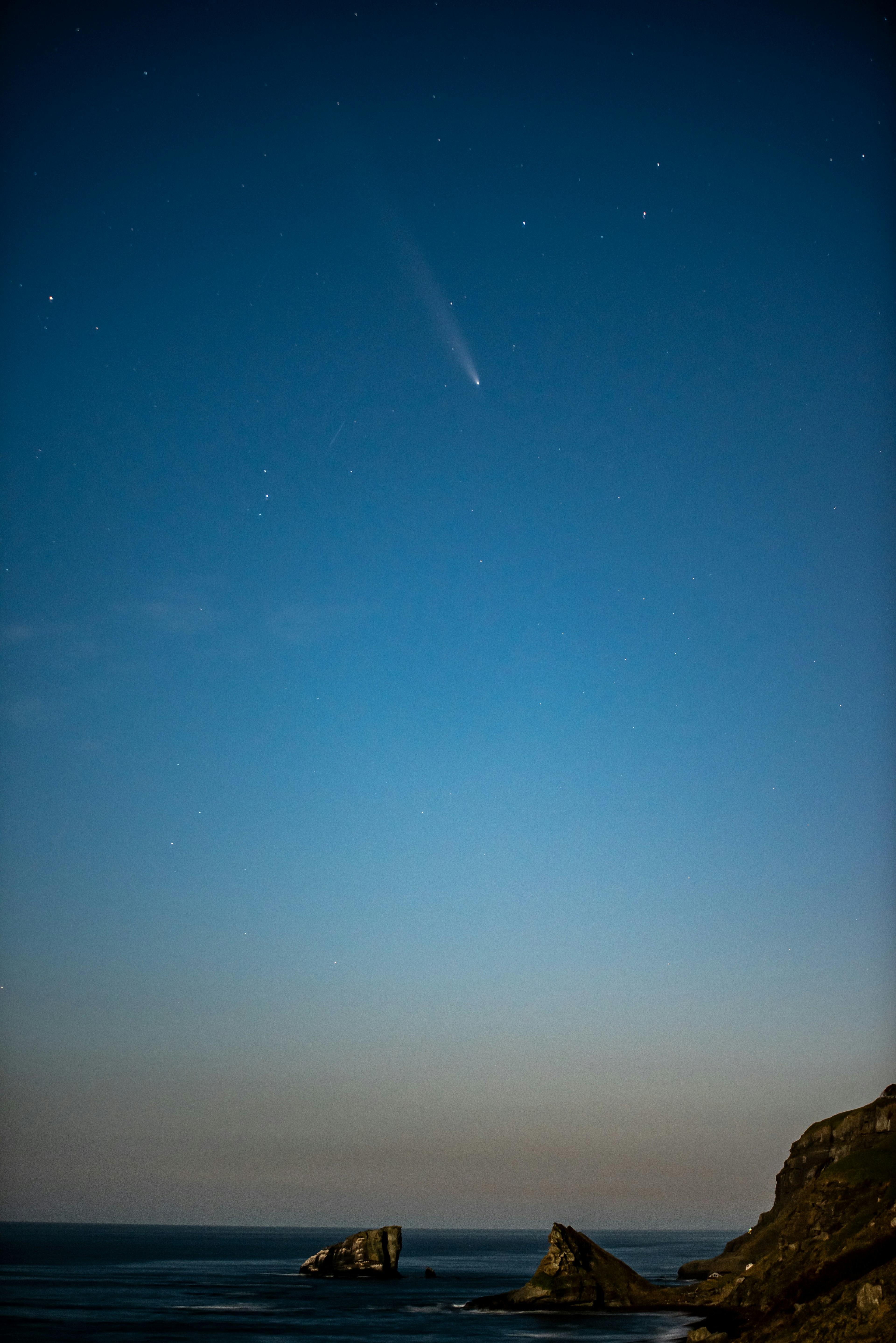 夜空に浮かぶ彗星と静かな海岸の景色