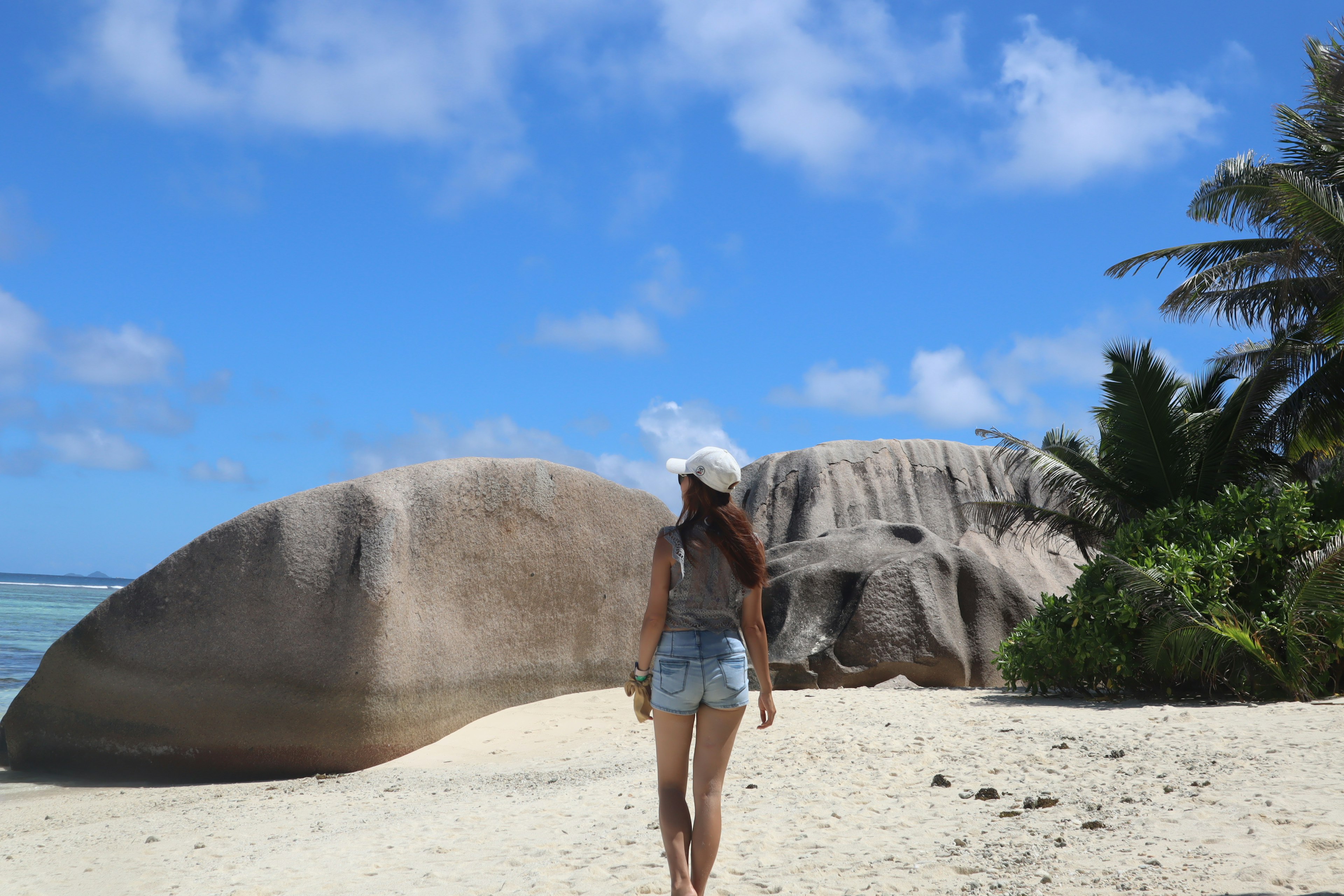 Una mujer caminando por una playa de arena con grandes rocas