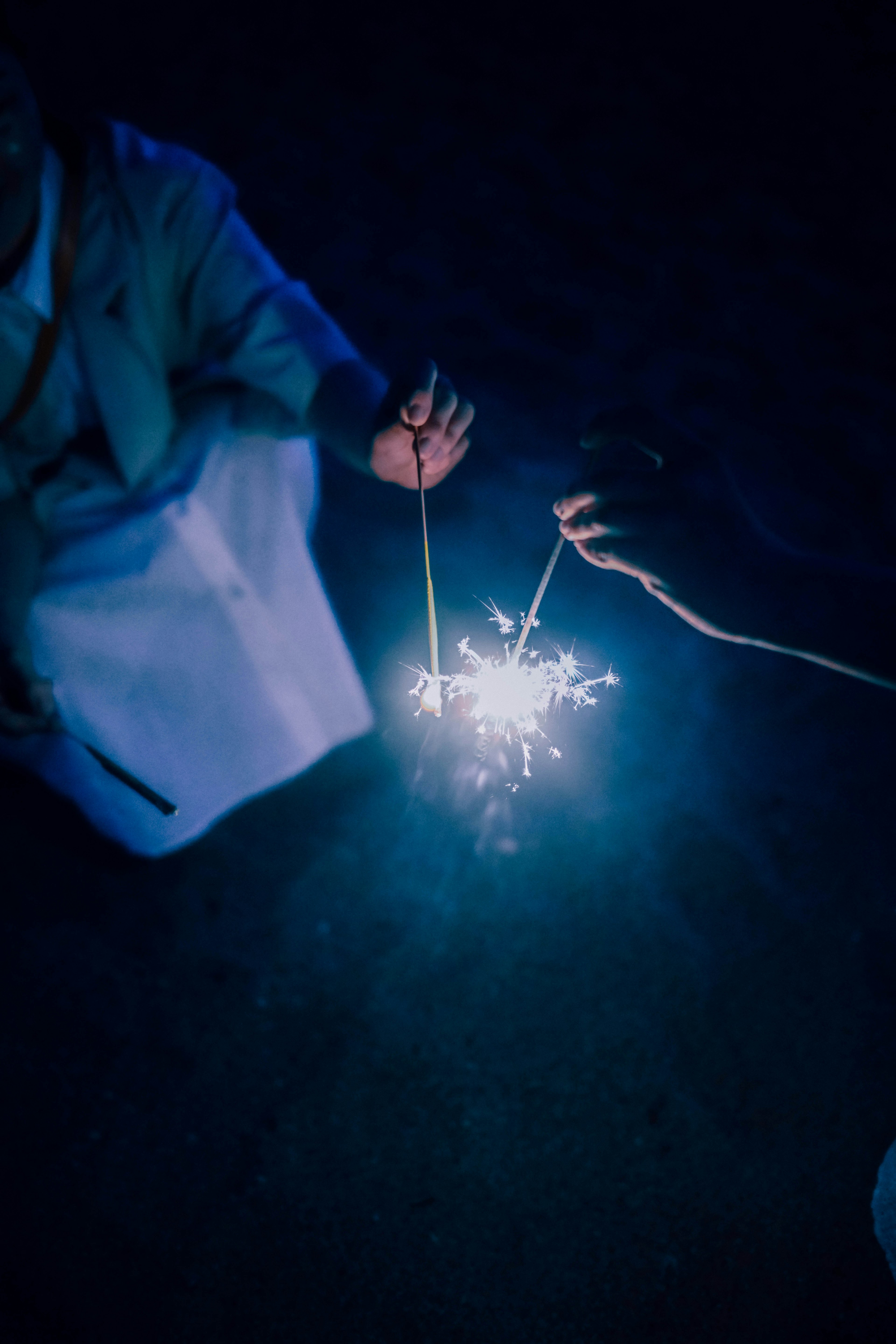 Due mani che tengono dei fuochi d'artificio al buio