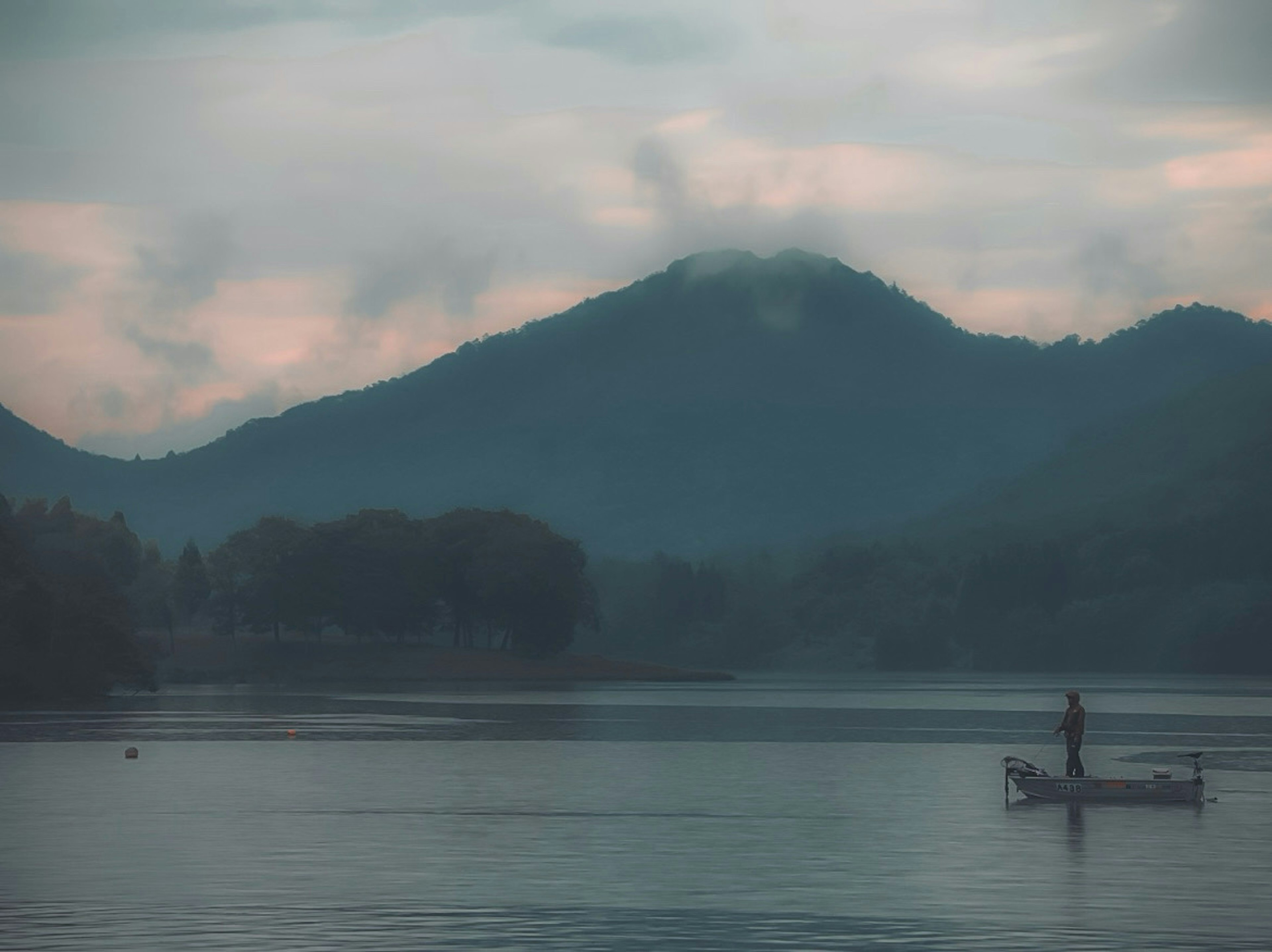 A tranquil lake scene featuring a small boat and mountains in the background