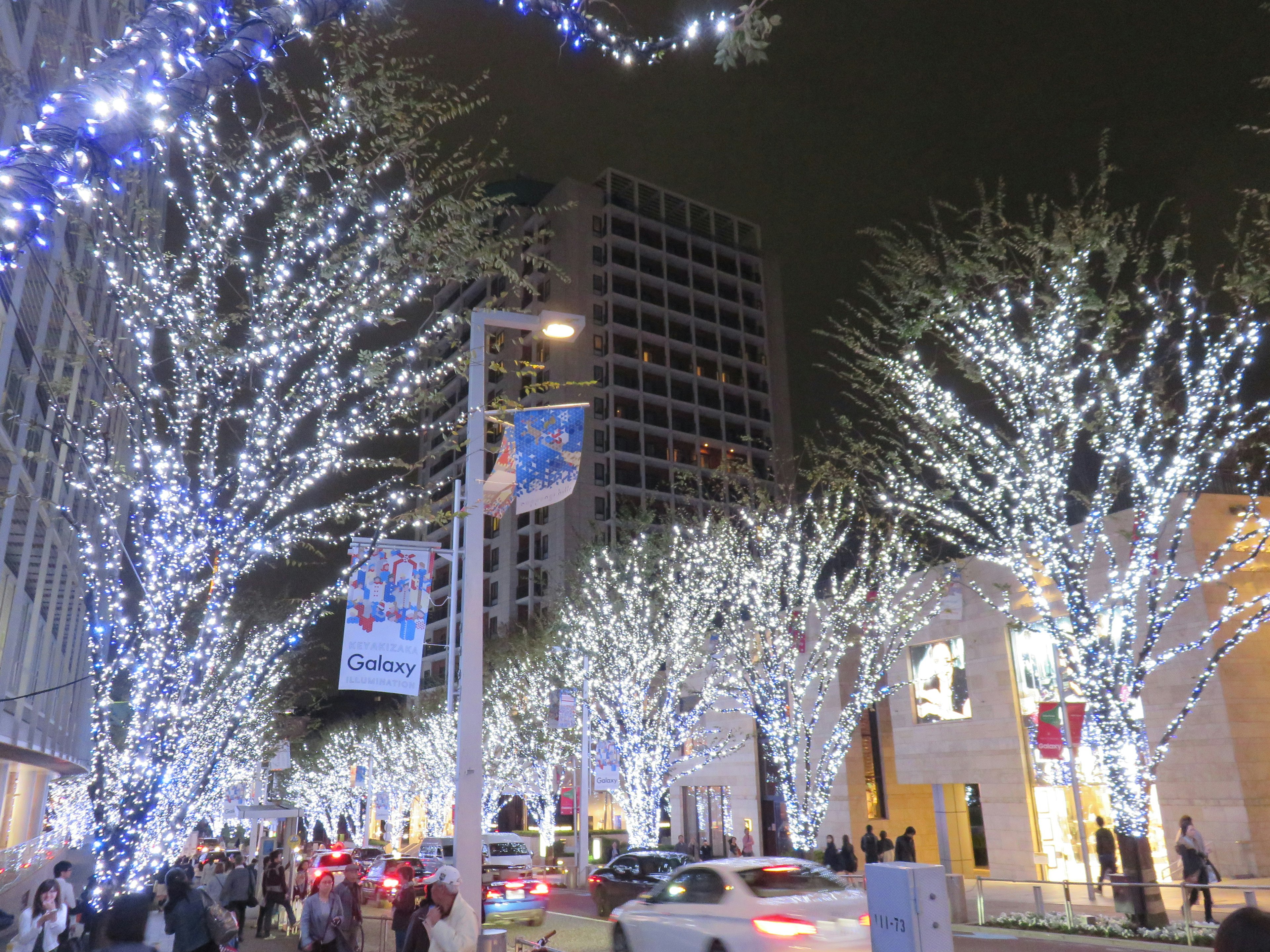 Illuminated trees with bright lights along a bustling street at night