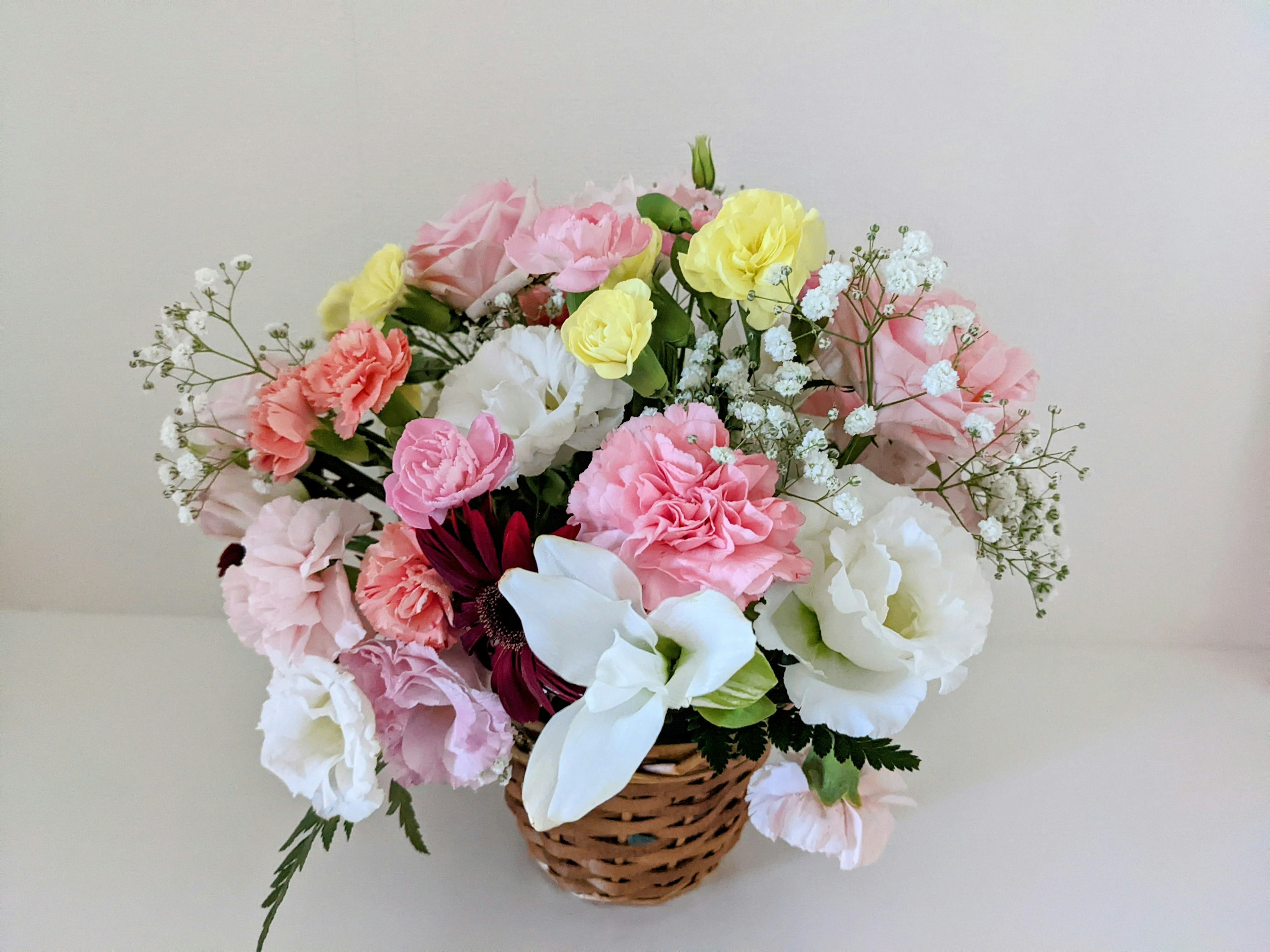 Arrangement floral coloré dans un panier posé sur un fond blanc