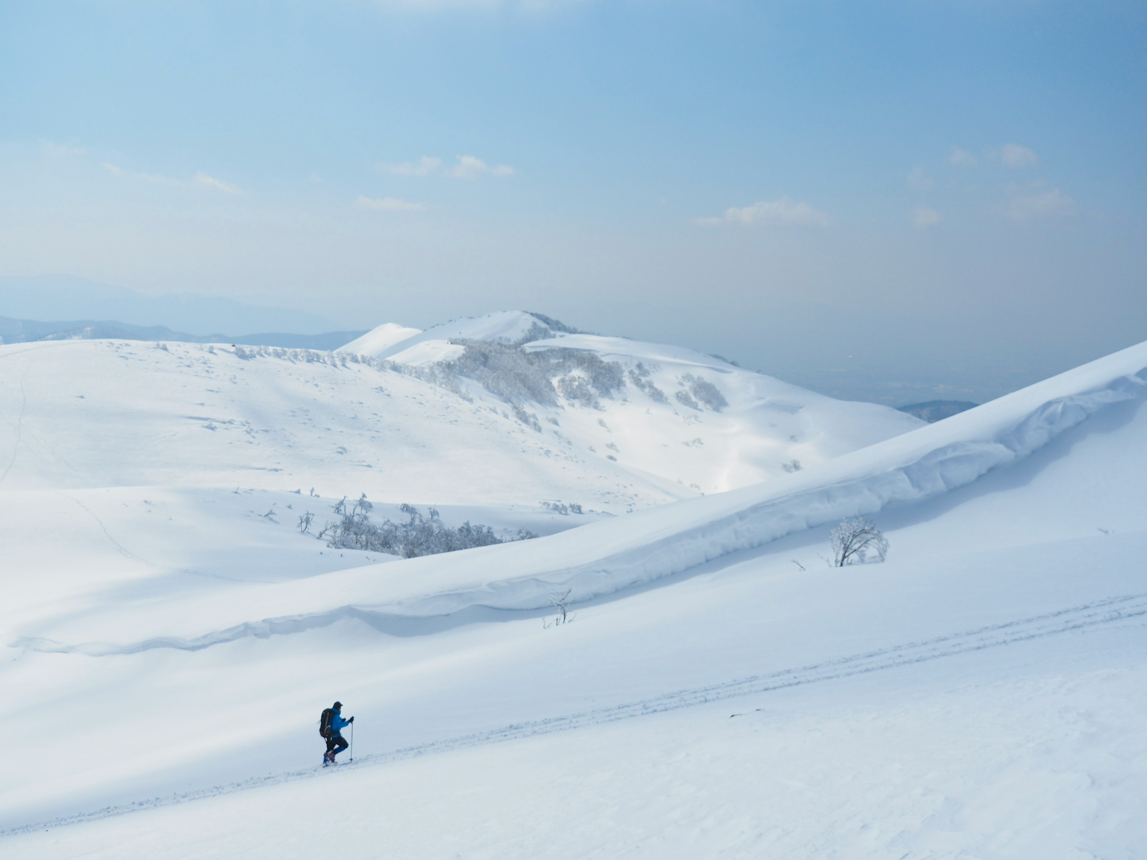 一名登山者在雪地中行走，背景是山脈