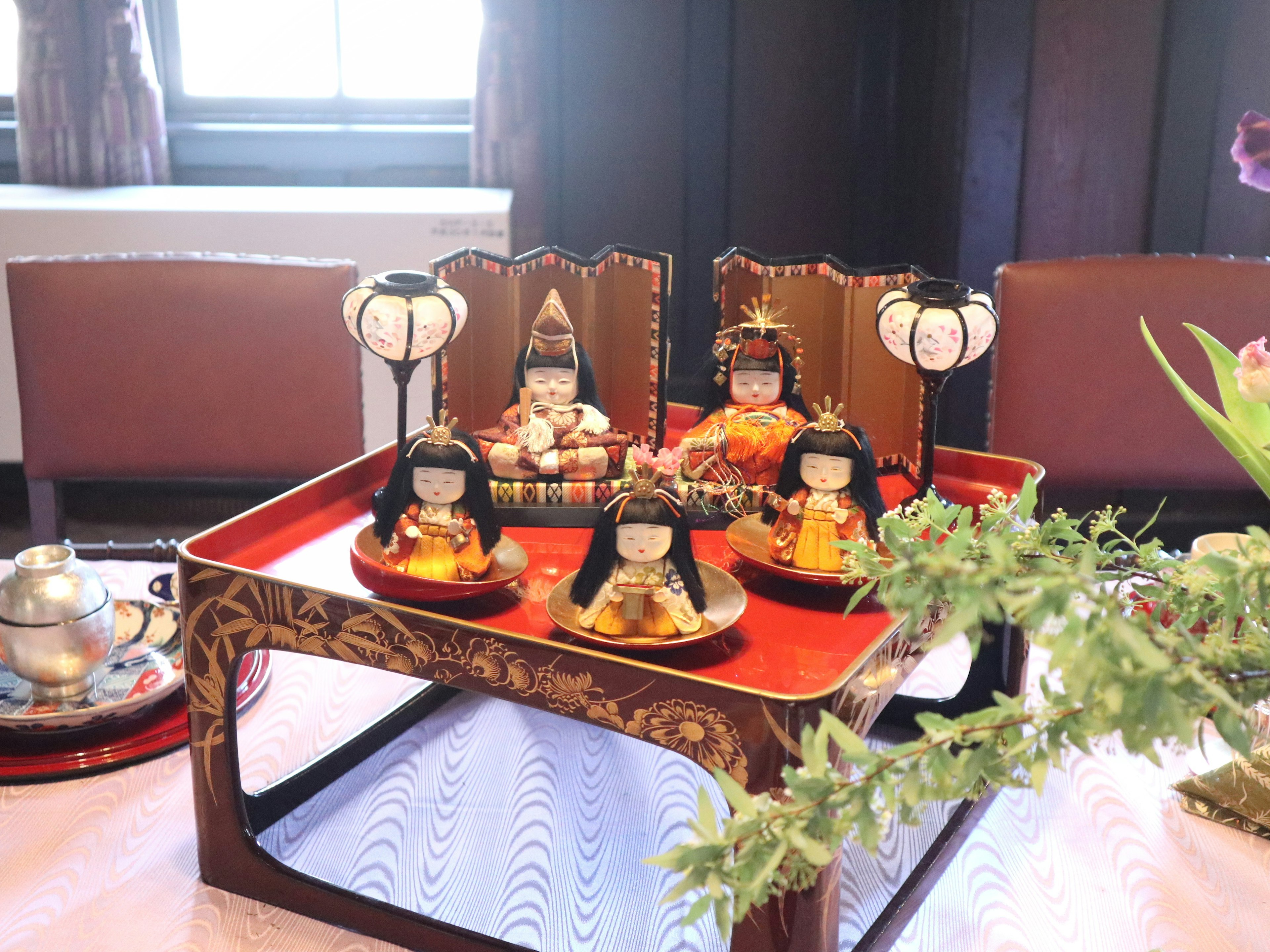 Colorful hina dolls displayed on a red tray for Hinamatsuri