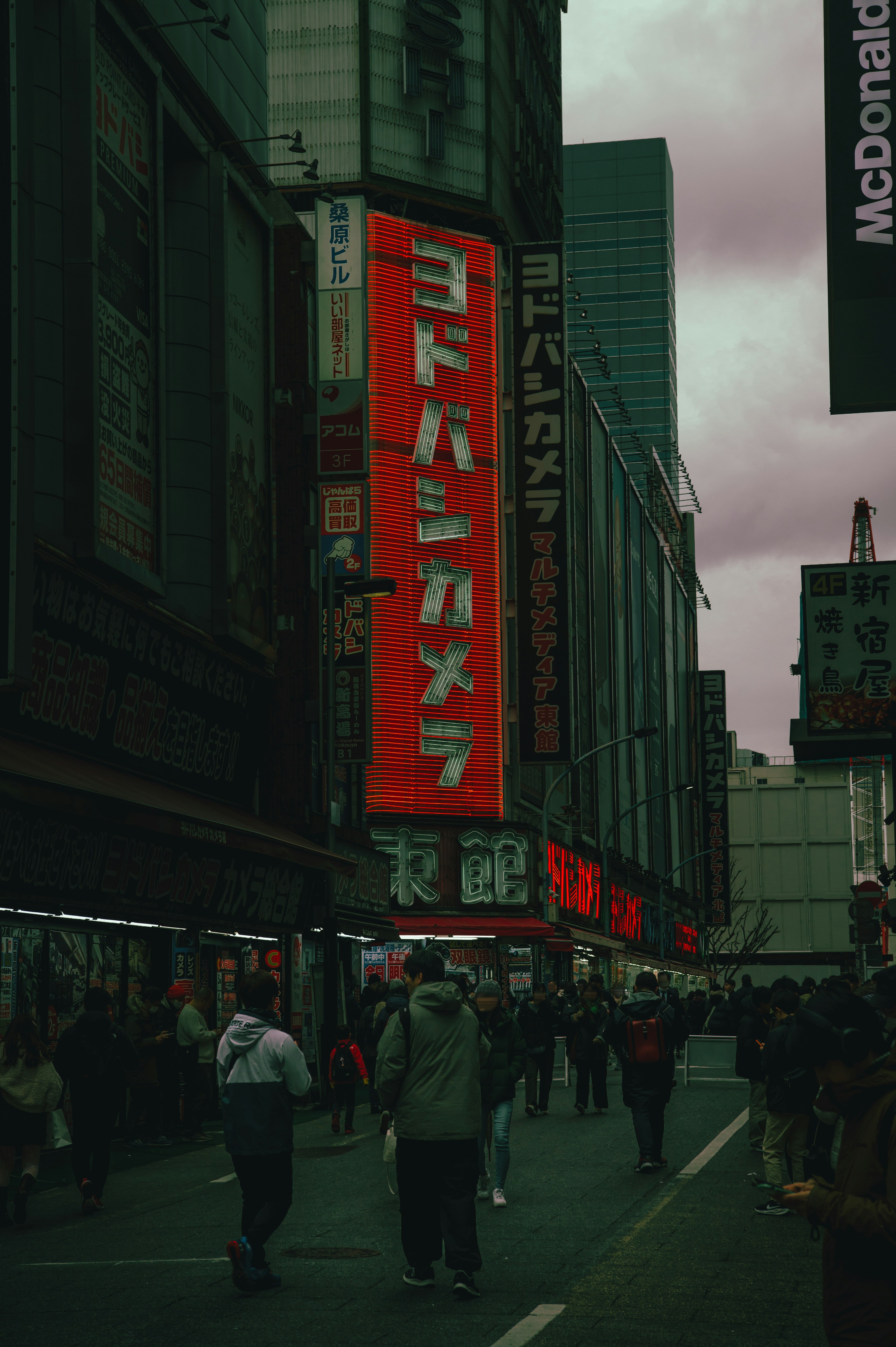 Kerumunan berjalan di jalan Tokyo dengan papan tanda merah Yodobashi Camera yang mencolok