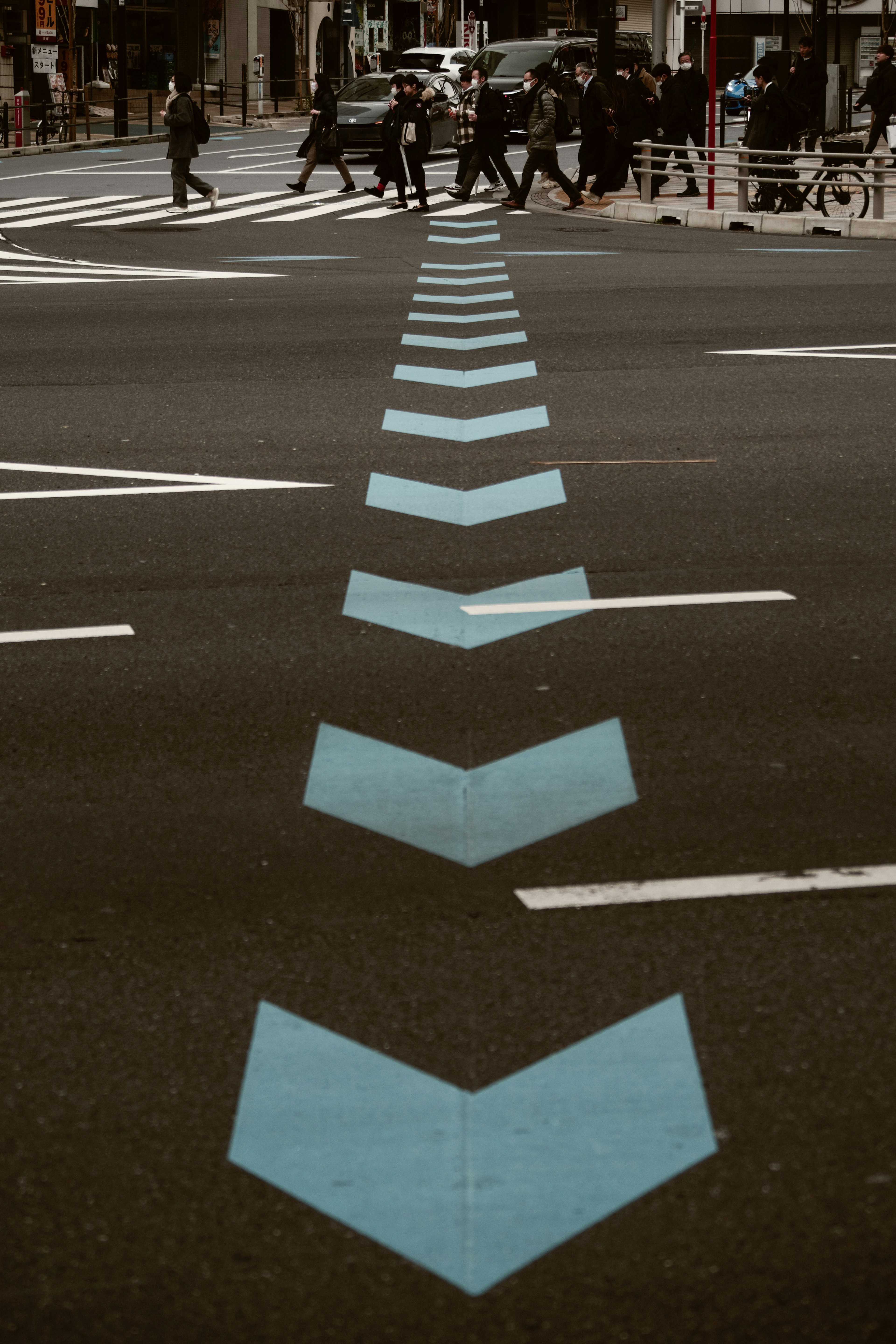 A view of a road with blue arrows directing traffic and pedestrians crossing