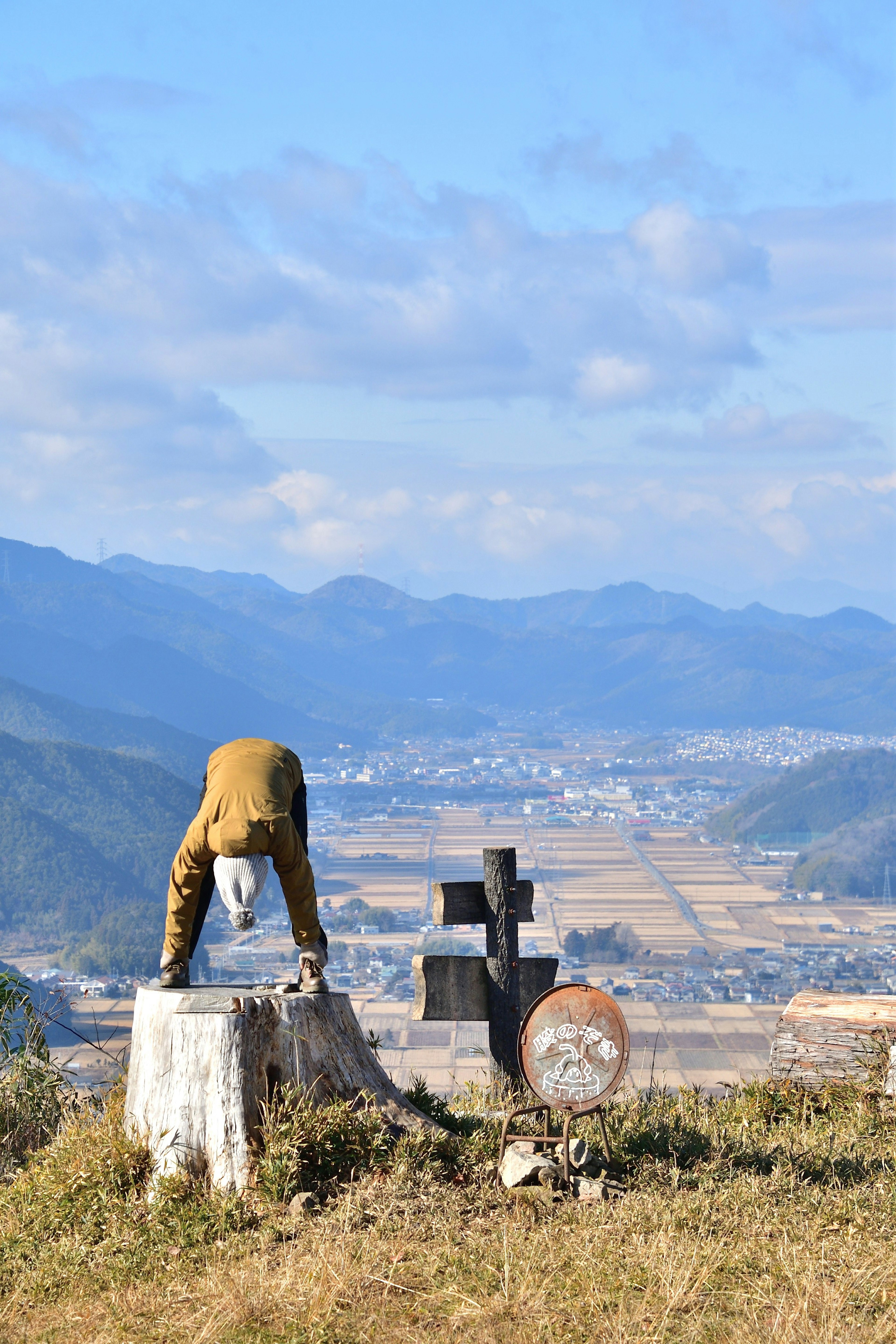 Eine Landschaft mit einer Puppe, die auf einem Bergkopf einen Handstand macht, neben einem kreuzförmigen Grabstein