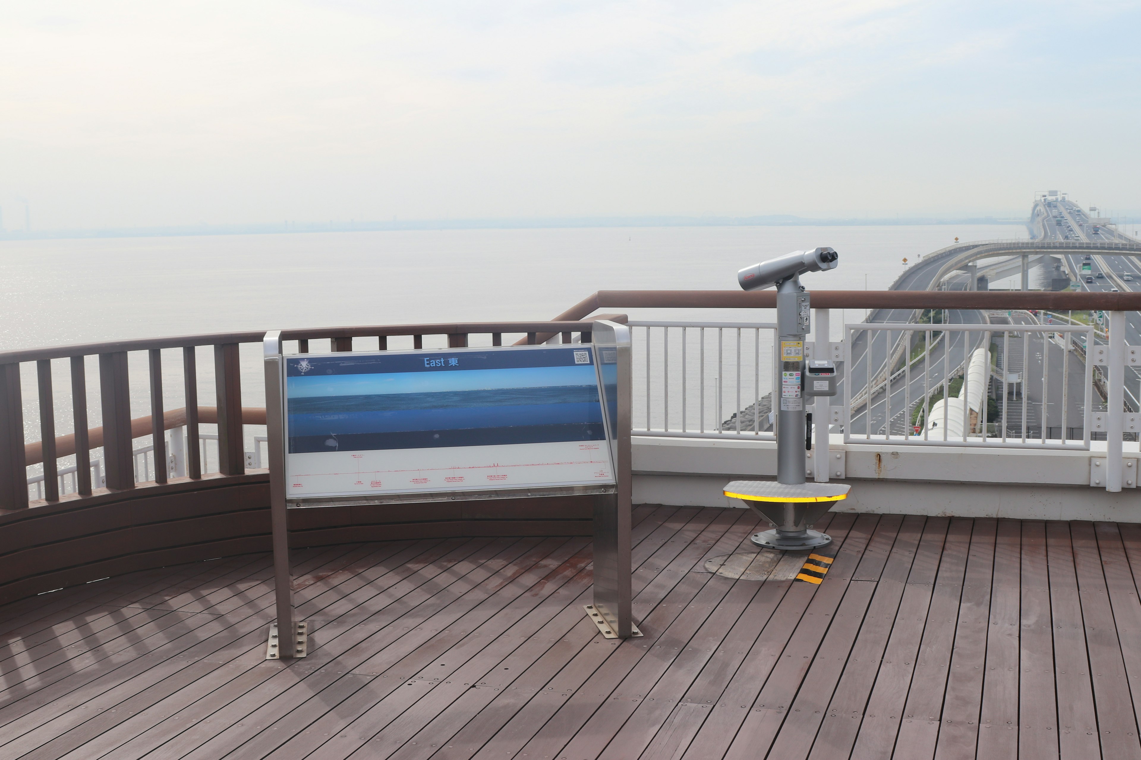 Plataforma de observación con un telescopio y un panel informativo sobre el mar