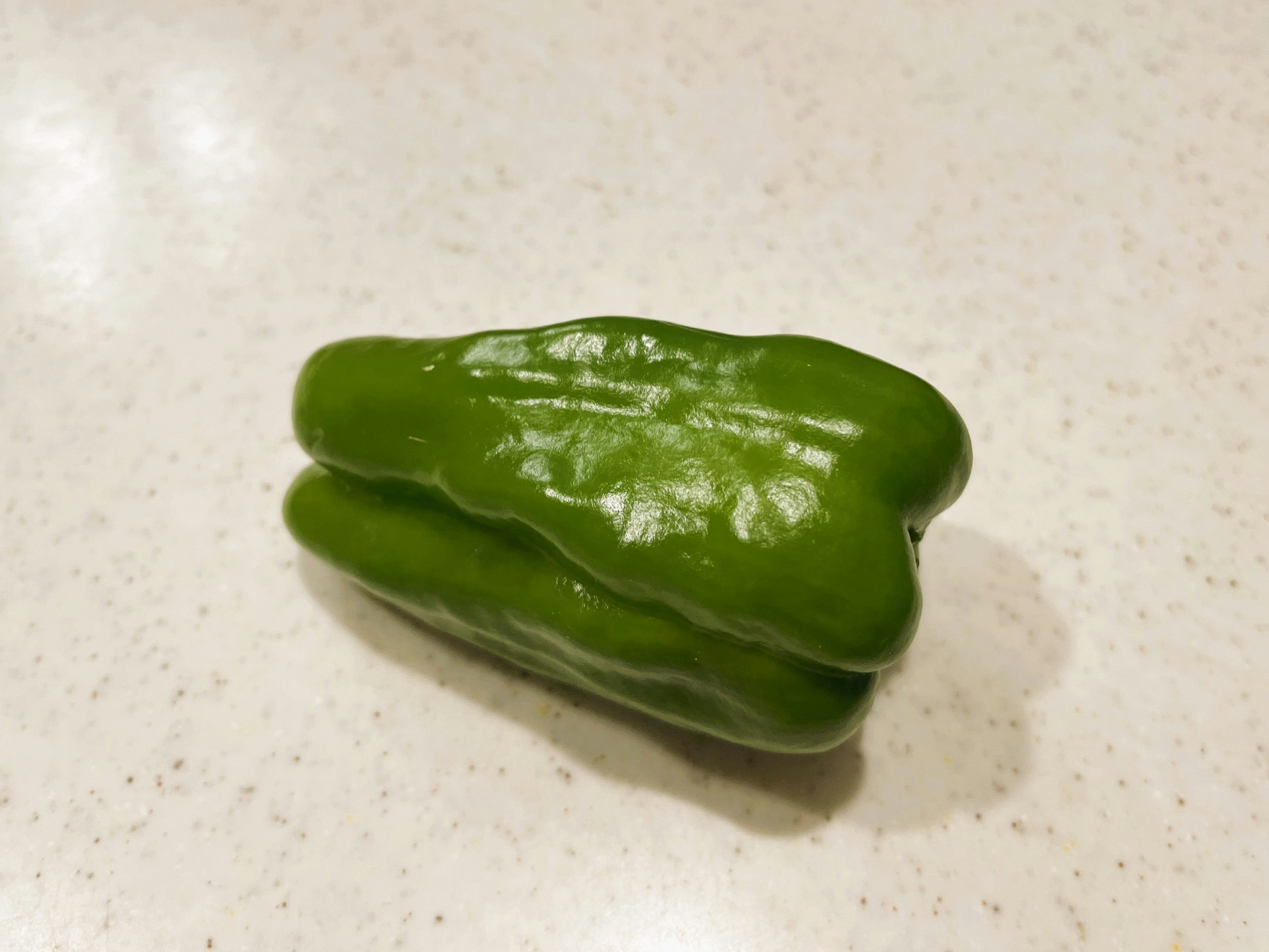 Unique shaped green pepper on a light countertop