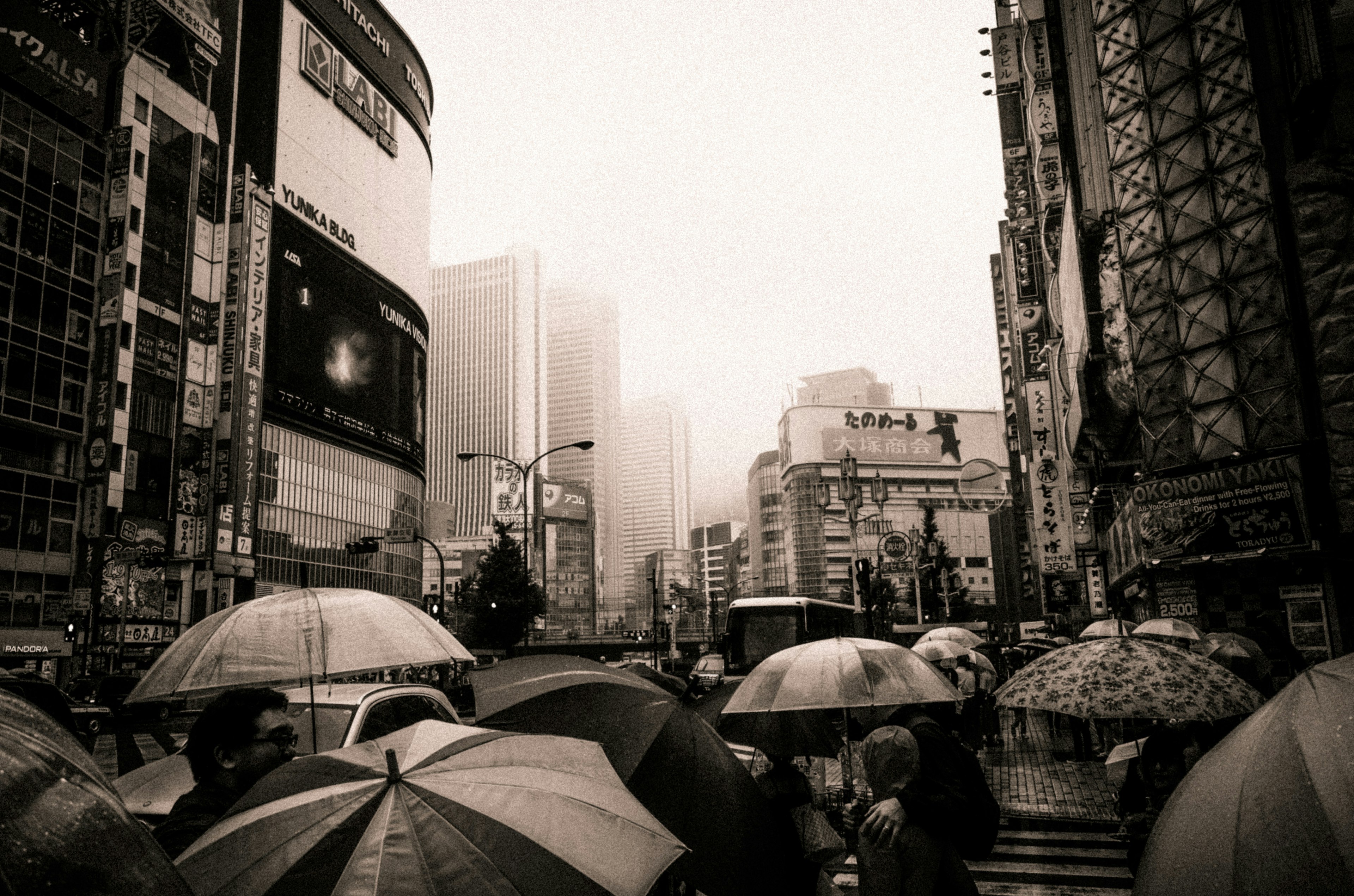 雨の中の渋谷の街並みと傘の群れ