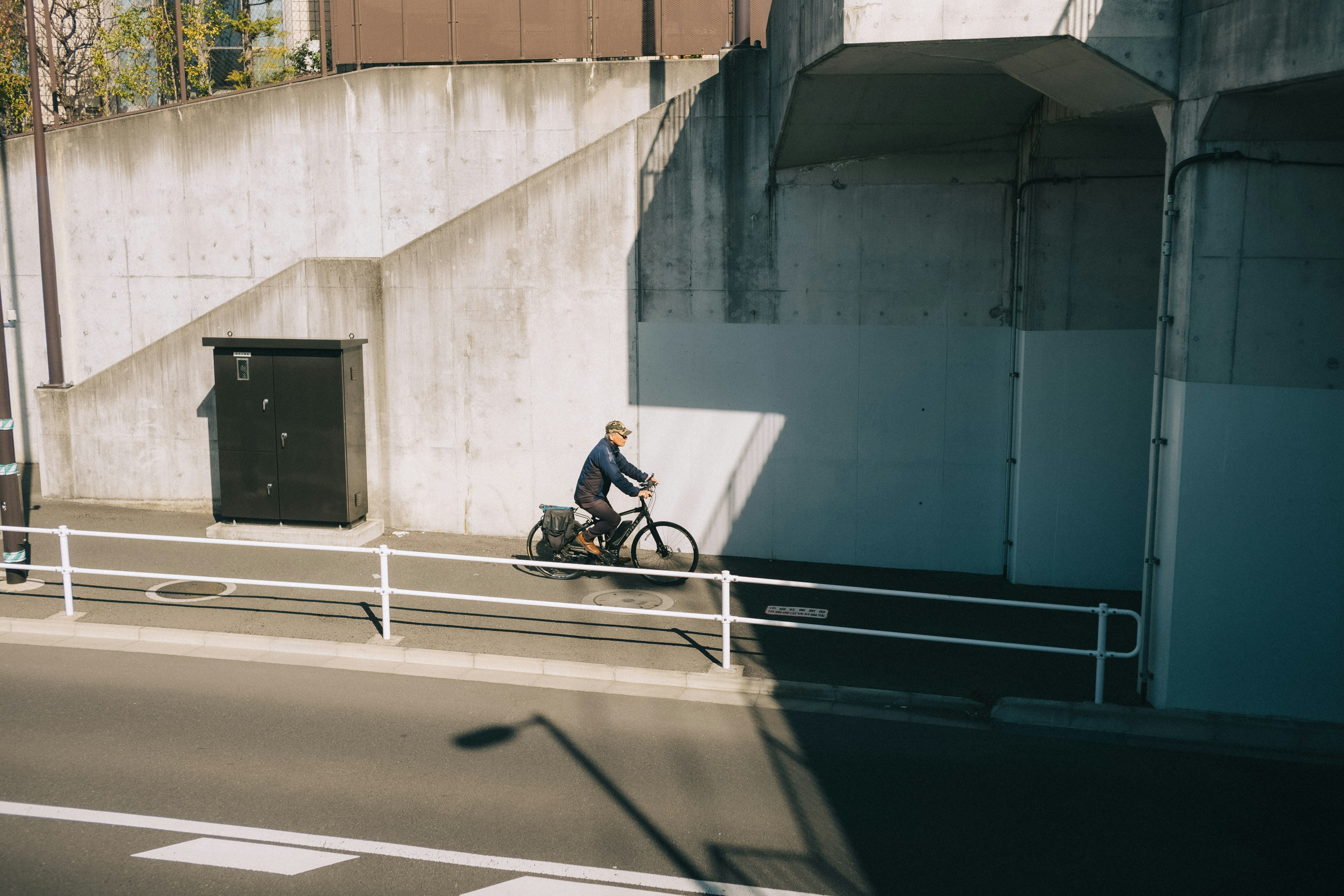 A person riding a bicycle near a concrete wall