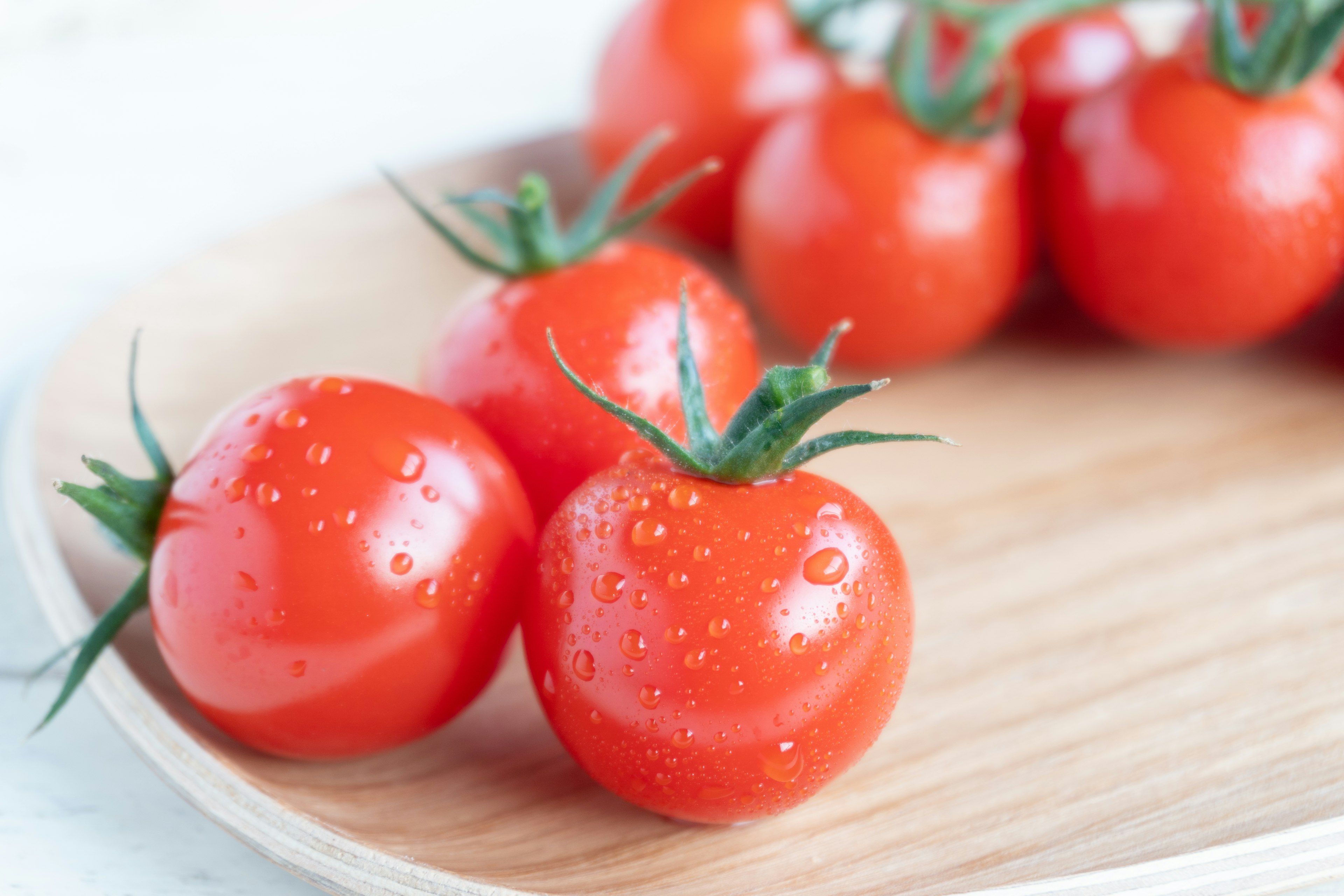 Fresh red tomatoes arranged on a wooden plate