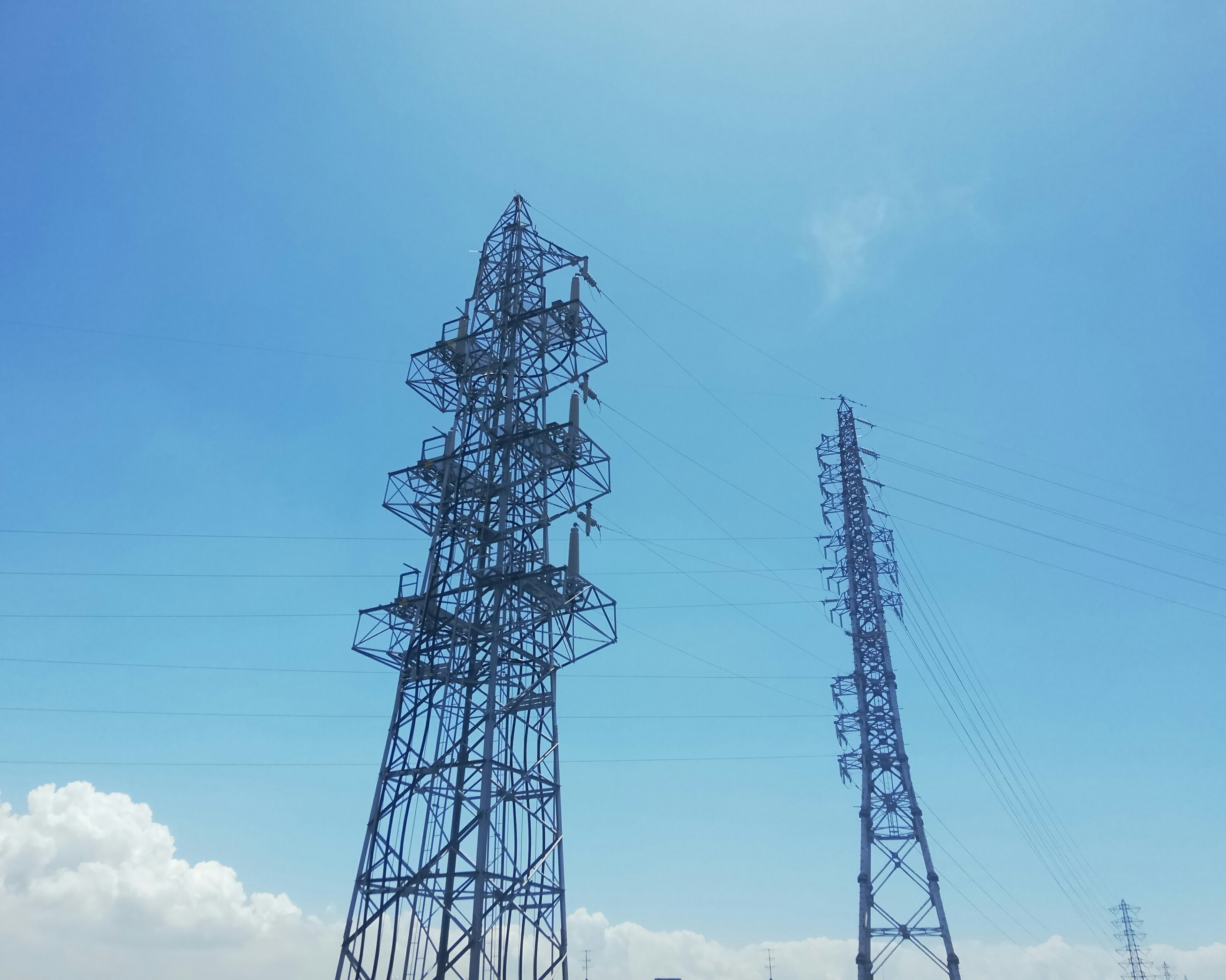 Silhouettes of two power towers under a blue sky