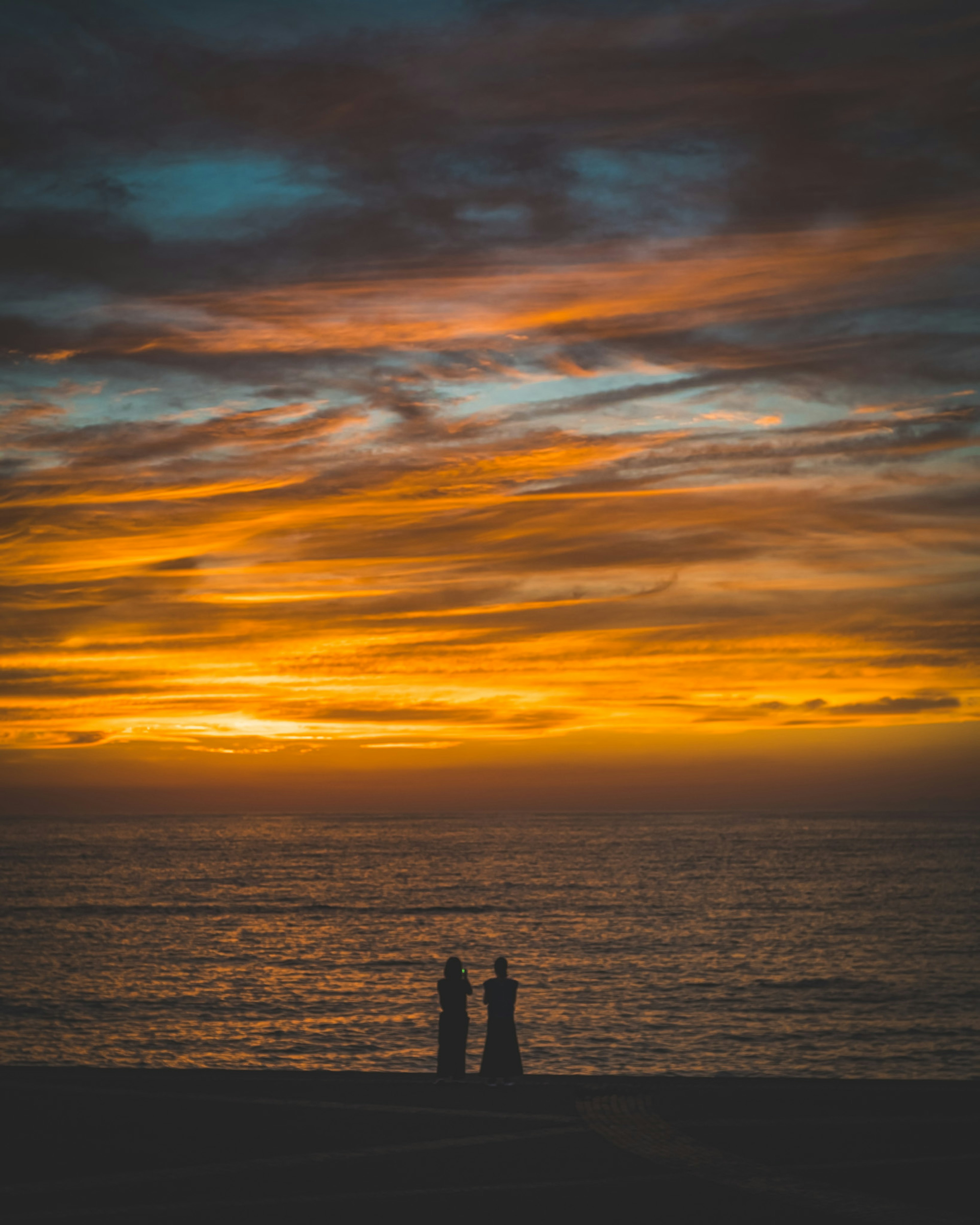 夕日を背景にした海辺での二人のシルエット