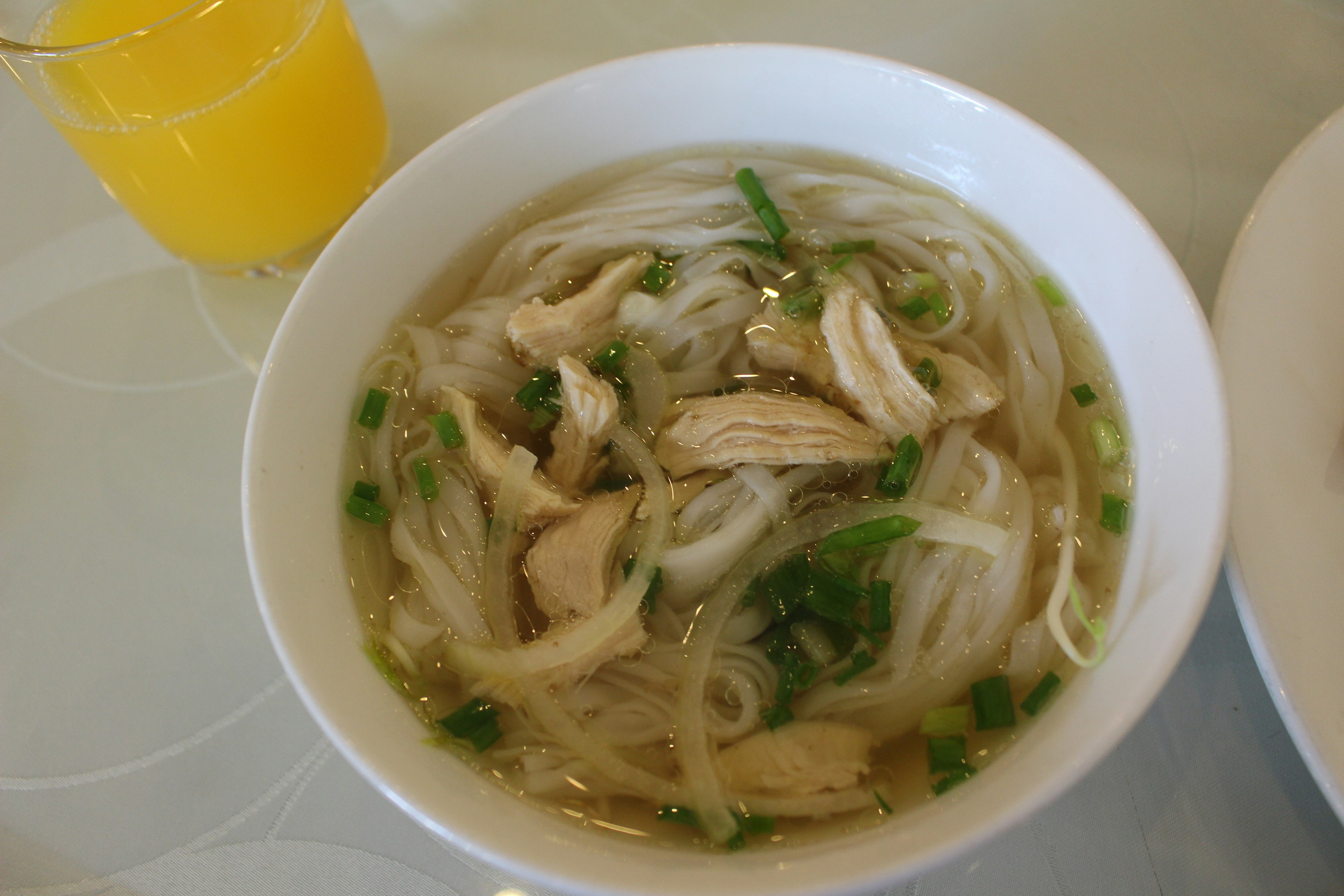 ชามก๋วยเตี๋ยวน้ำใสที่มีไก่และต้นหอม