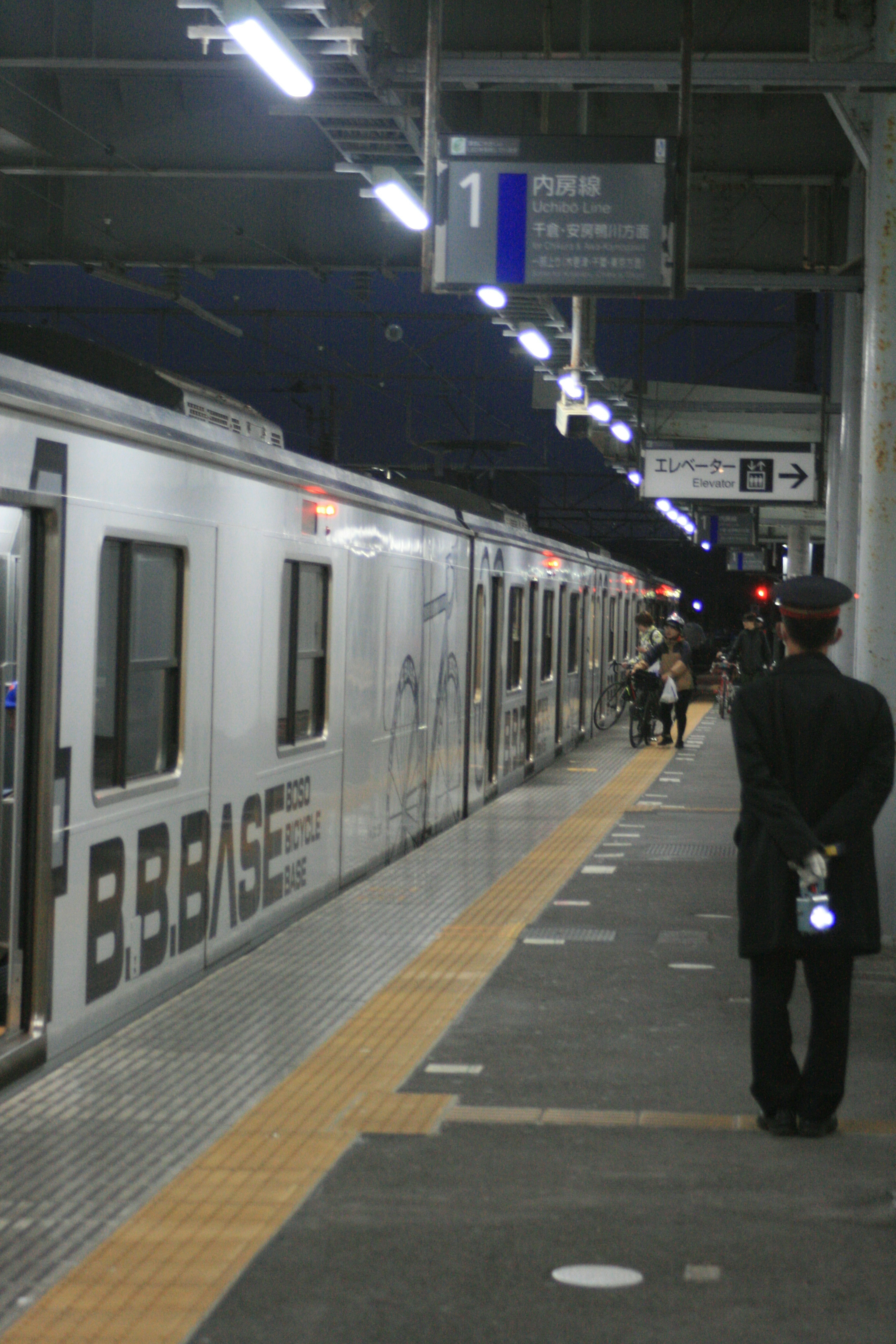 A person waiting at a train station with a train in the background at night