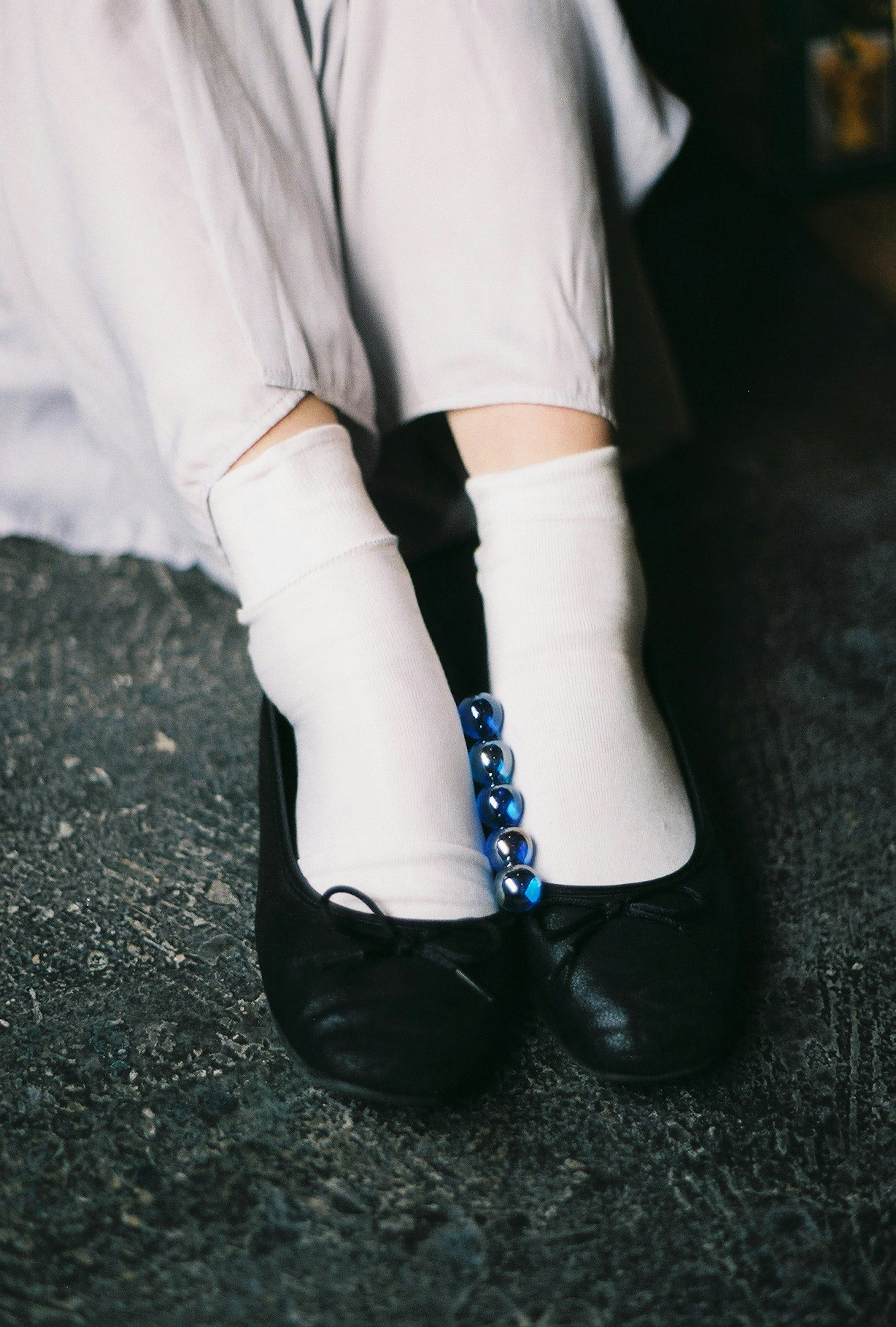 Feet in white socks and black ballet flats