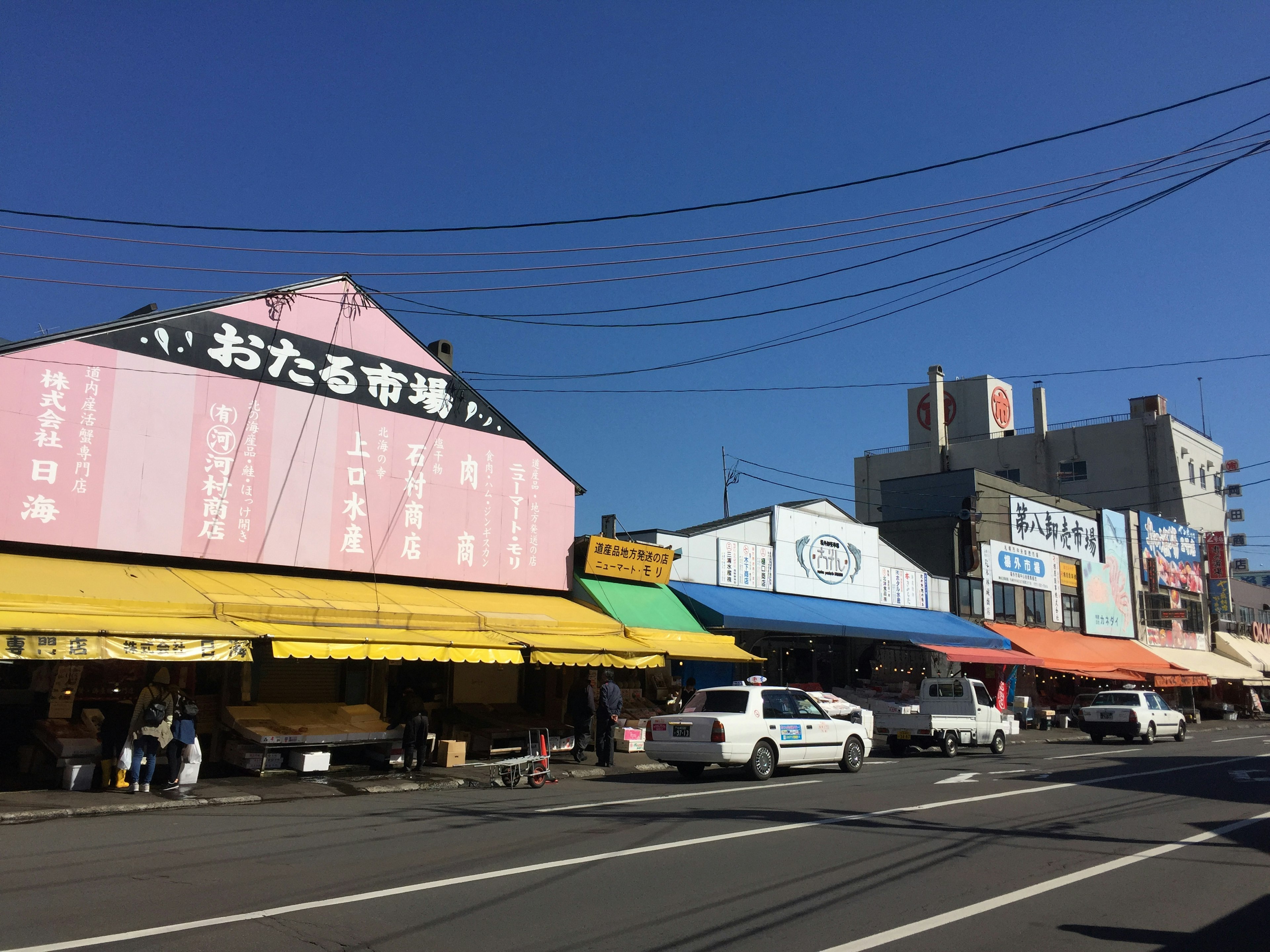 Calle alineada con coloridos puestos y tiendas bajo un cielo azul