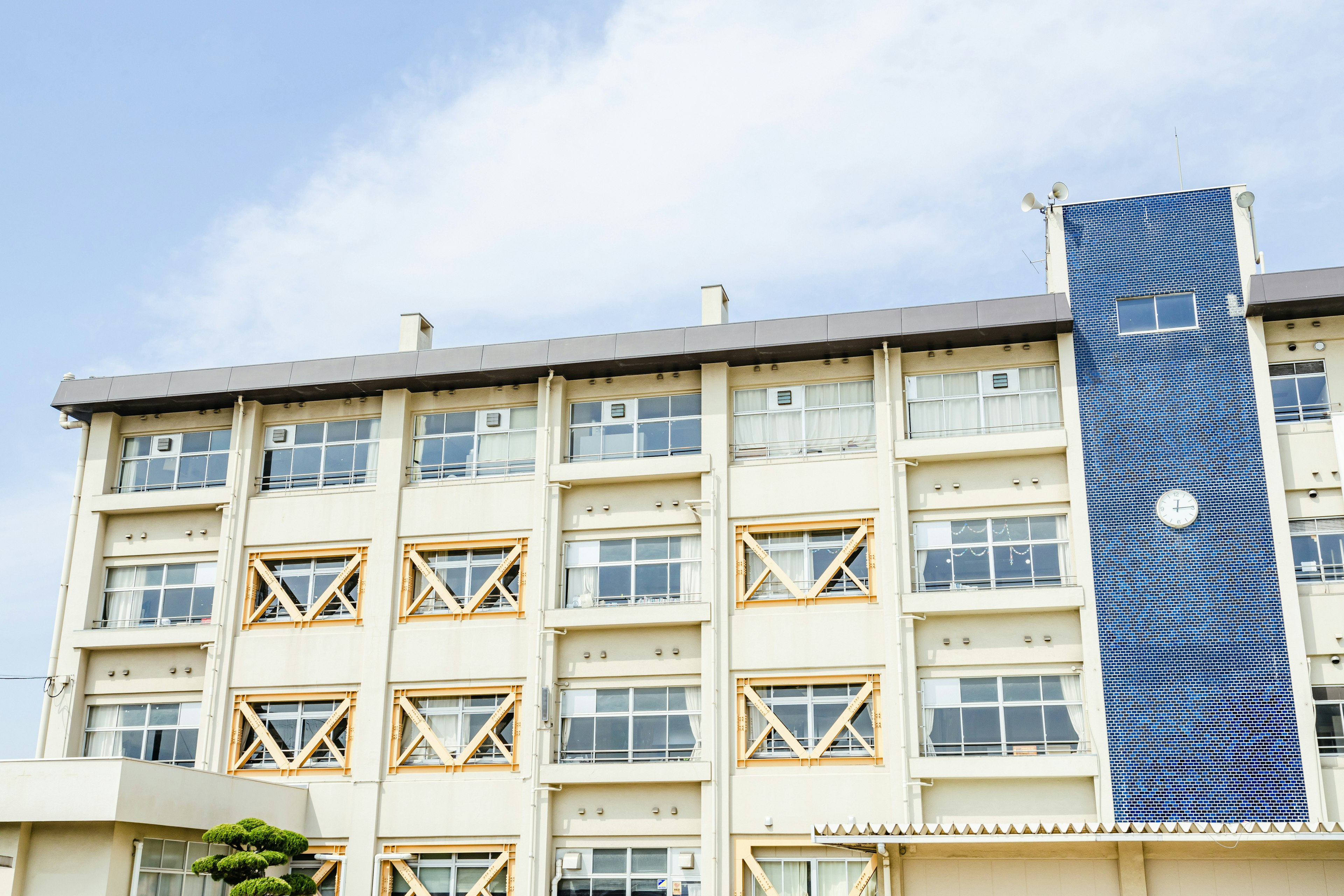 Modern building exterior under blue sky featuring large windows and unique wooden design