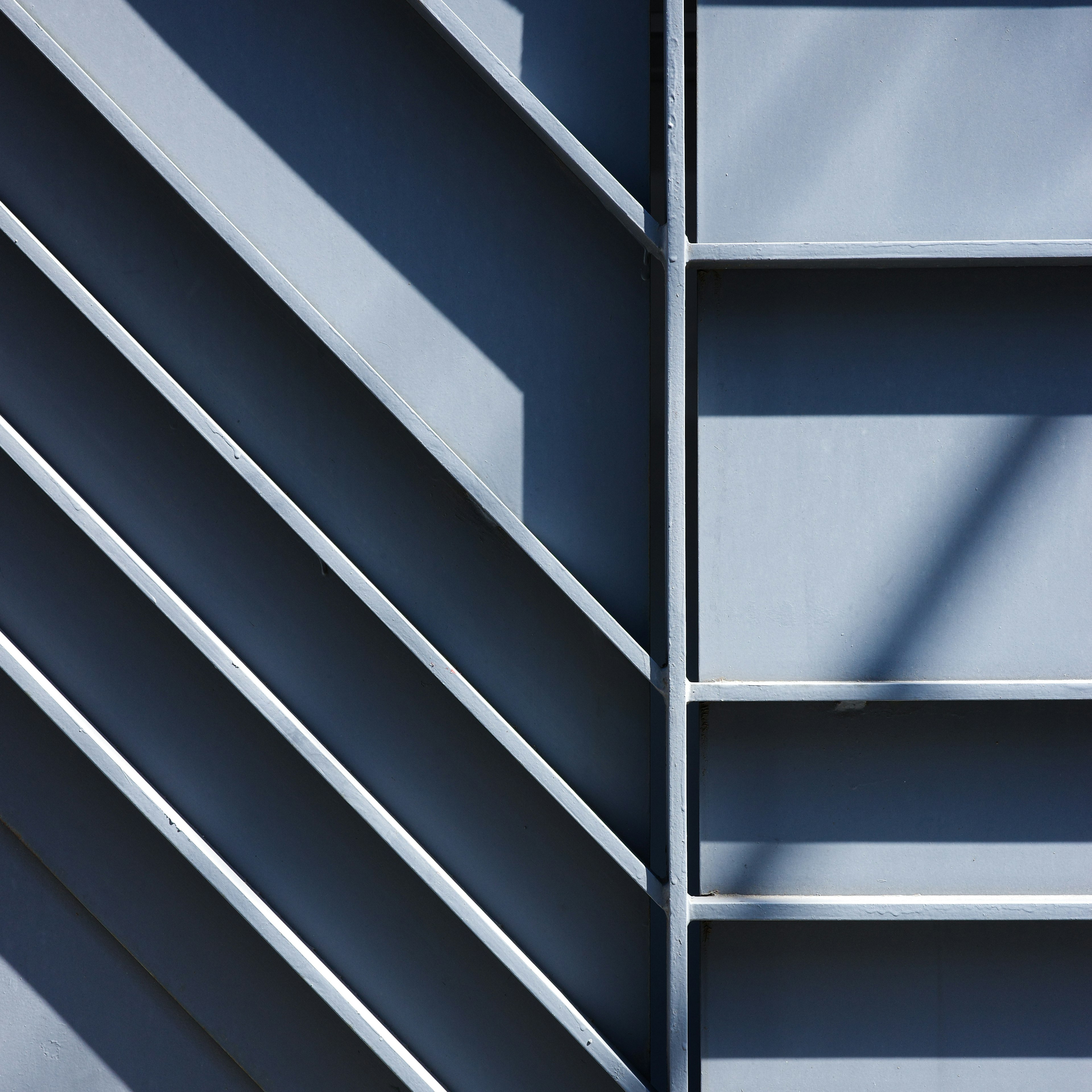 Diagonale Linien und Schatten auf einer blauen Metallwand