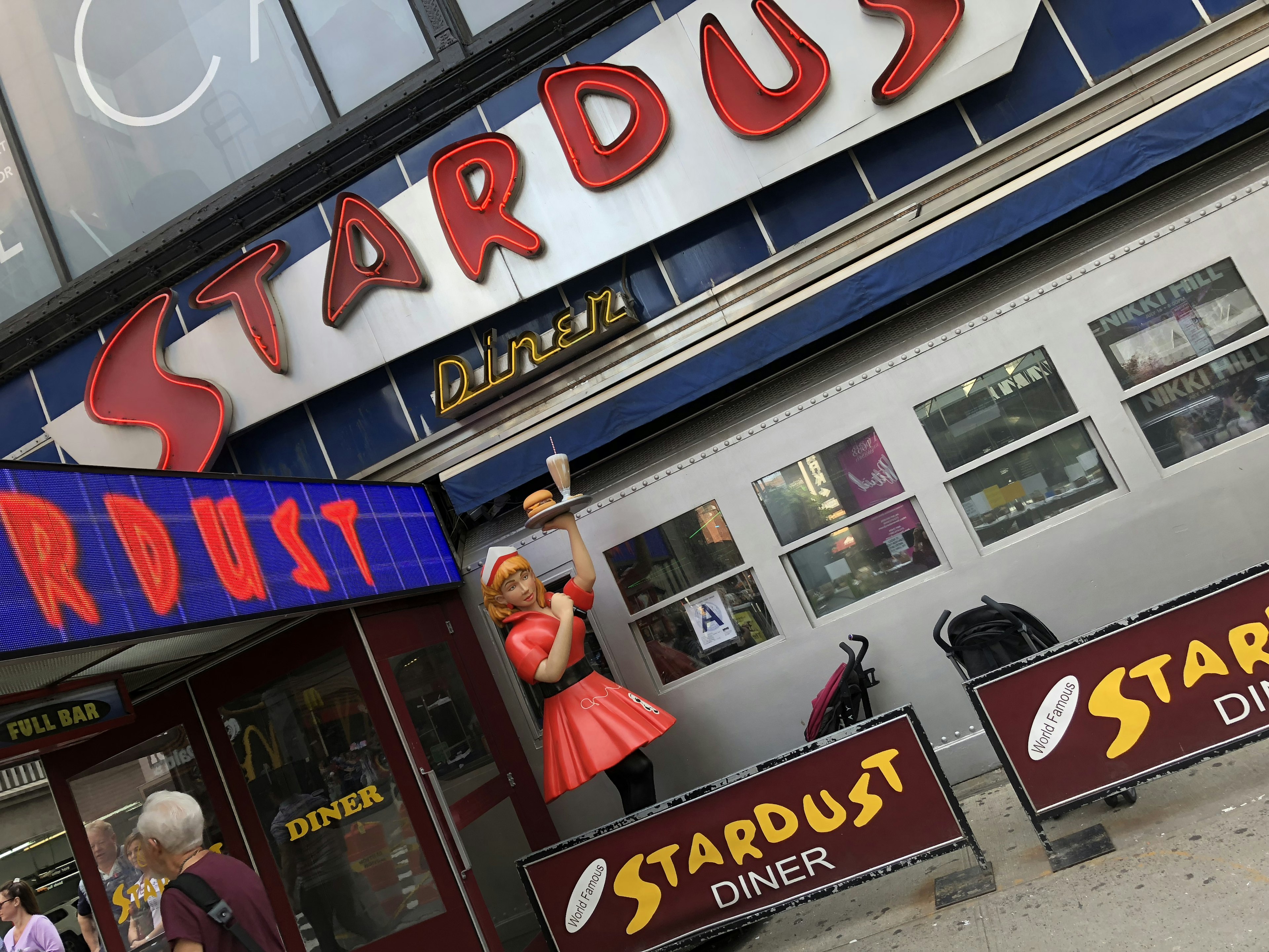 Ngoại thất của Stardust Diner với biển hiệu đầy màu sắc và trang trí búp bê