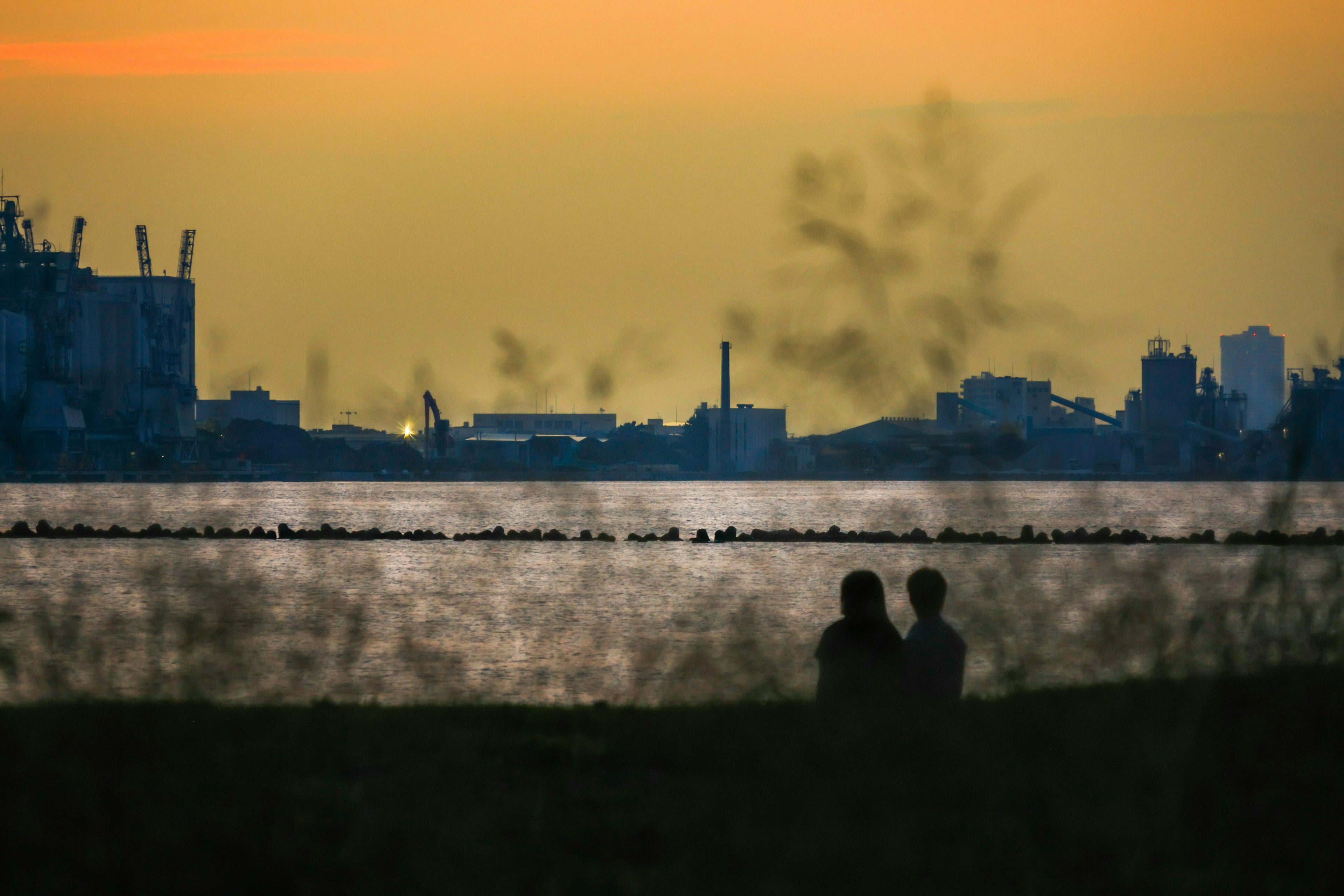 Silhouette of a couple against a sunset with reflections on the water