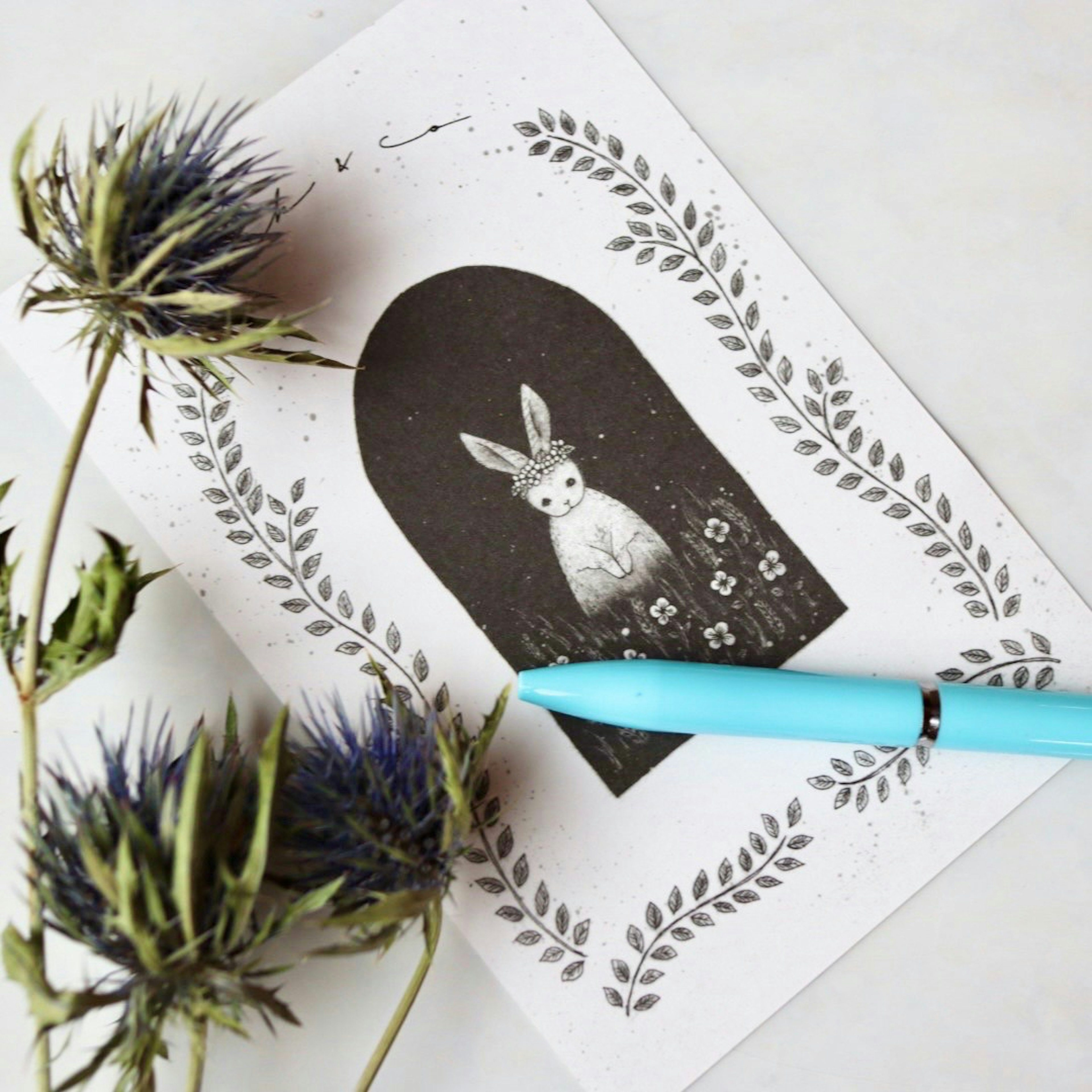 Illustration d'un lapin blanc entouré de fleurs avec un stylo bleu