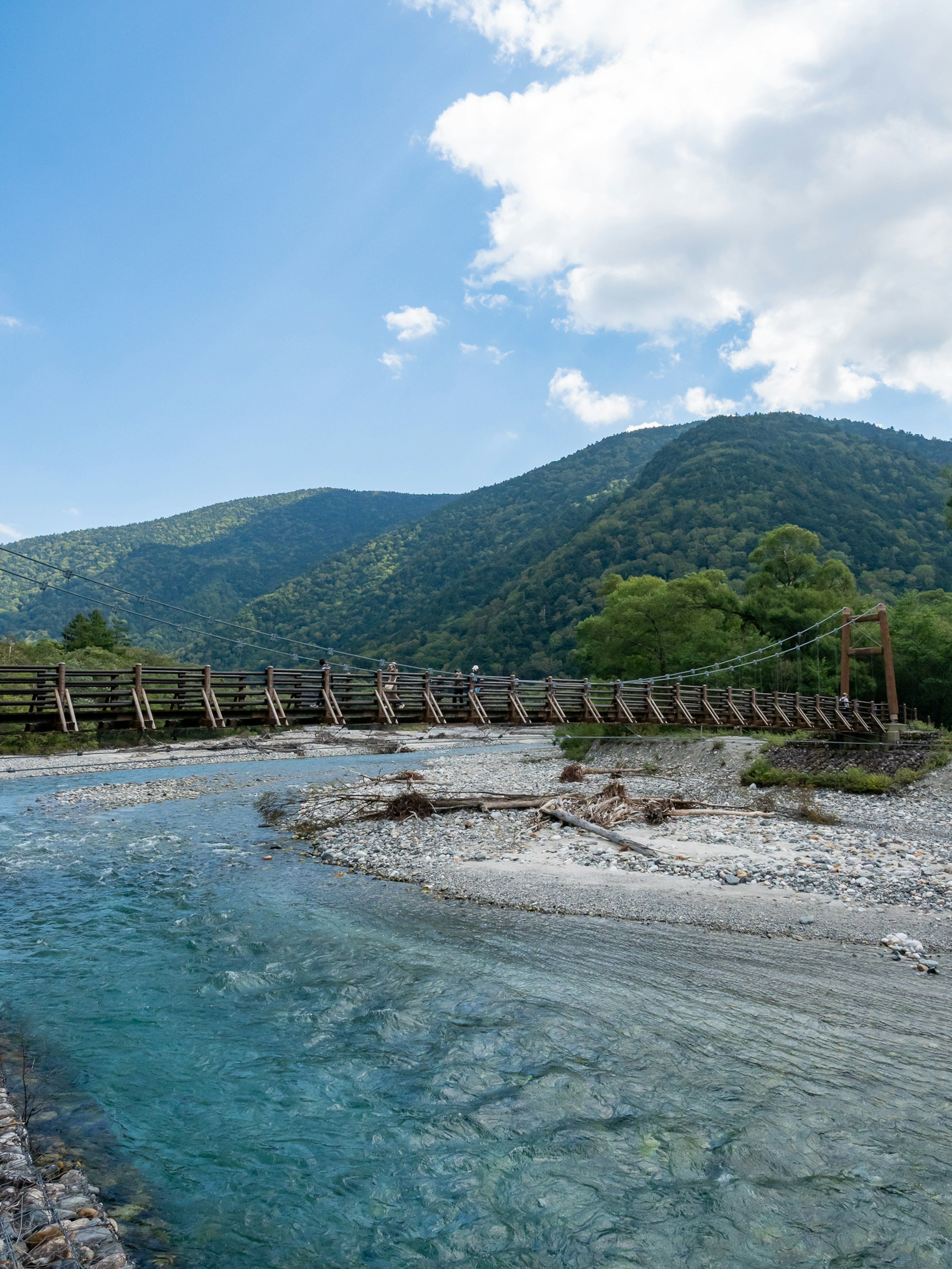 Scenic view of a blue river with a wooden bridge and mountains