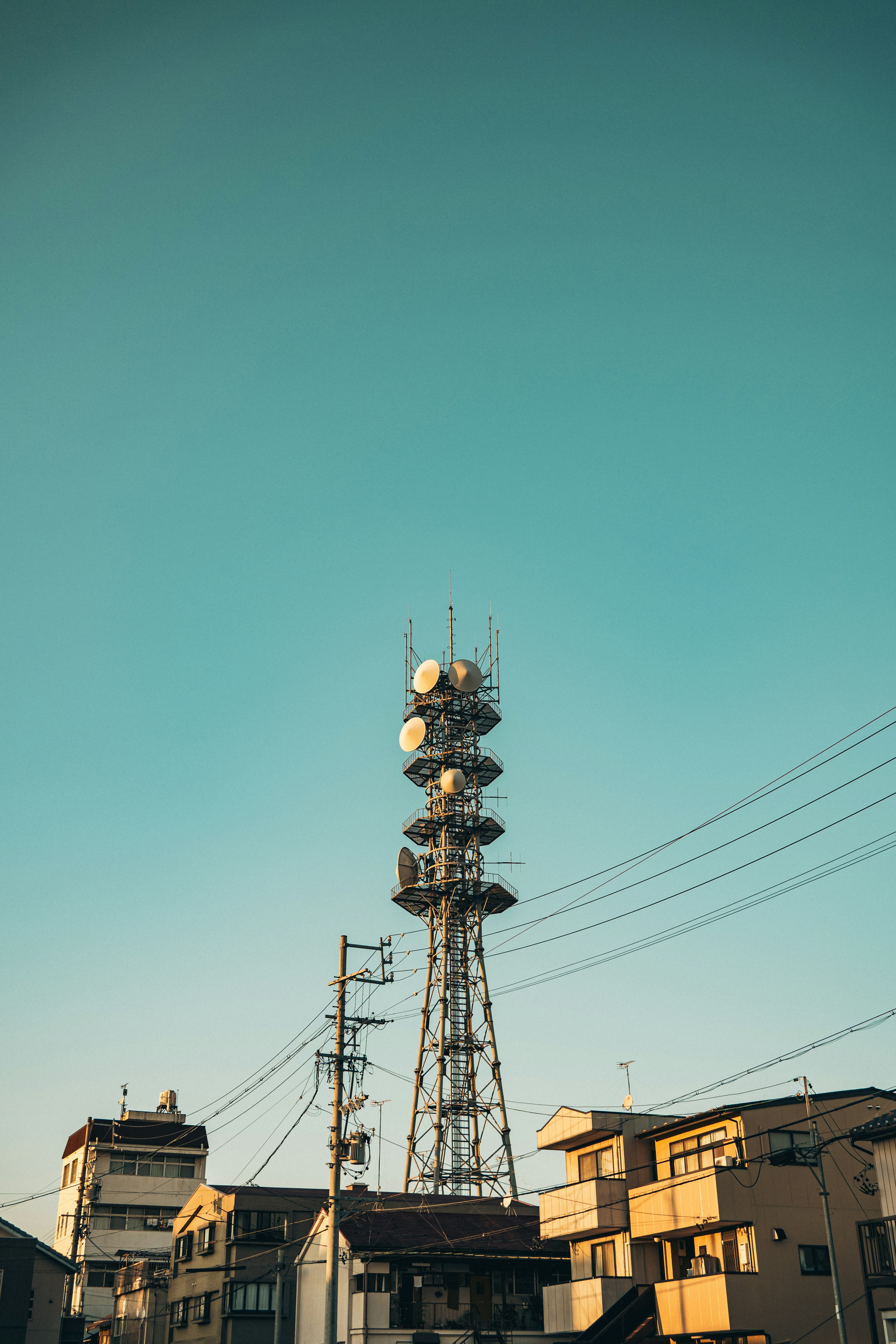 Torre de comunicaciones contra un cielo azul claro con edificios circundantes