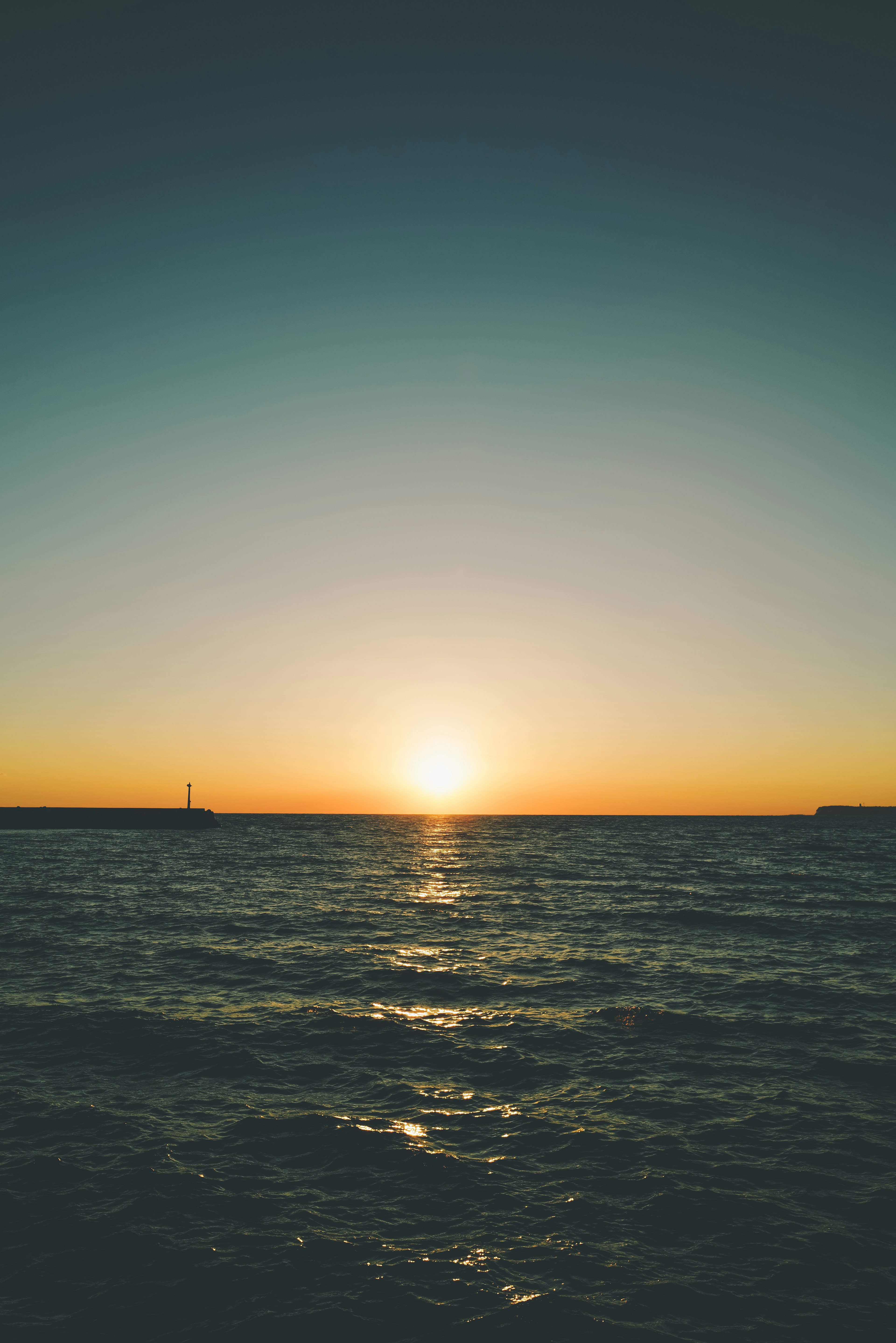 海の水平線に沈む美しい夕日と穏やかな波の風景