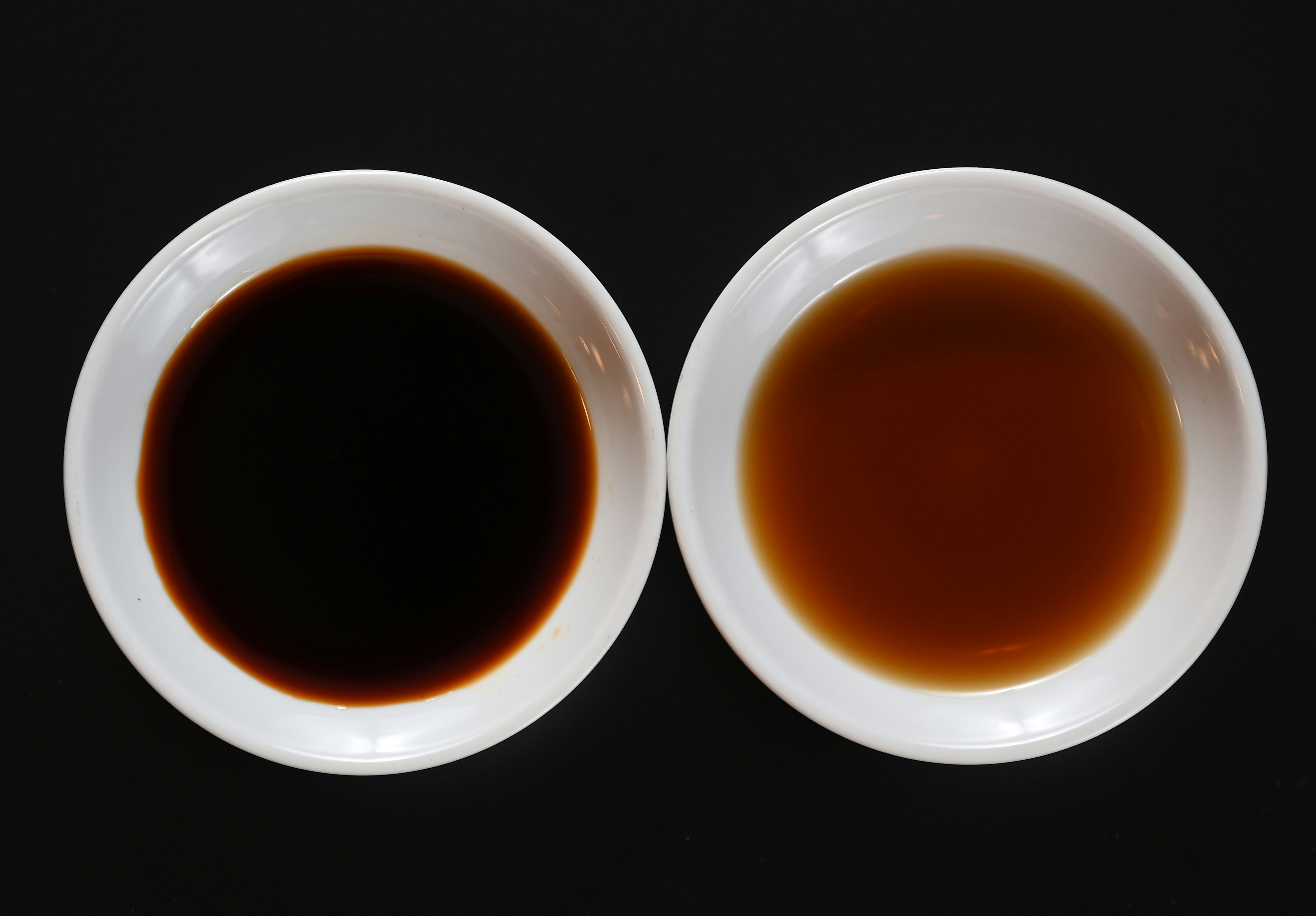 Two white bowls on a black background containing different colored liquids