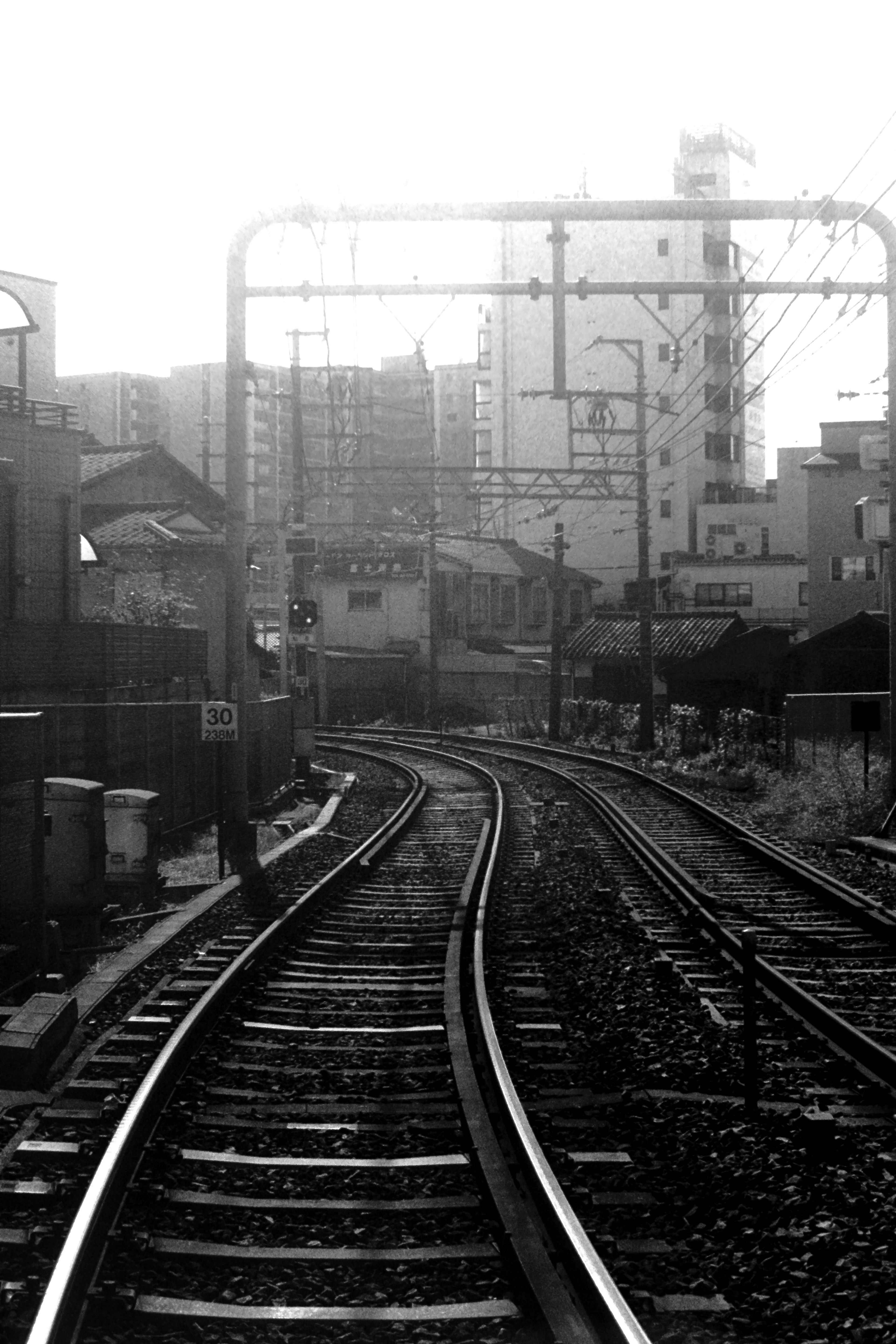 Curving railway tracks in a cityscape in black and white