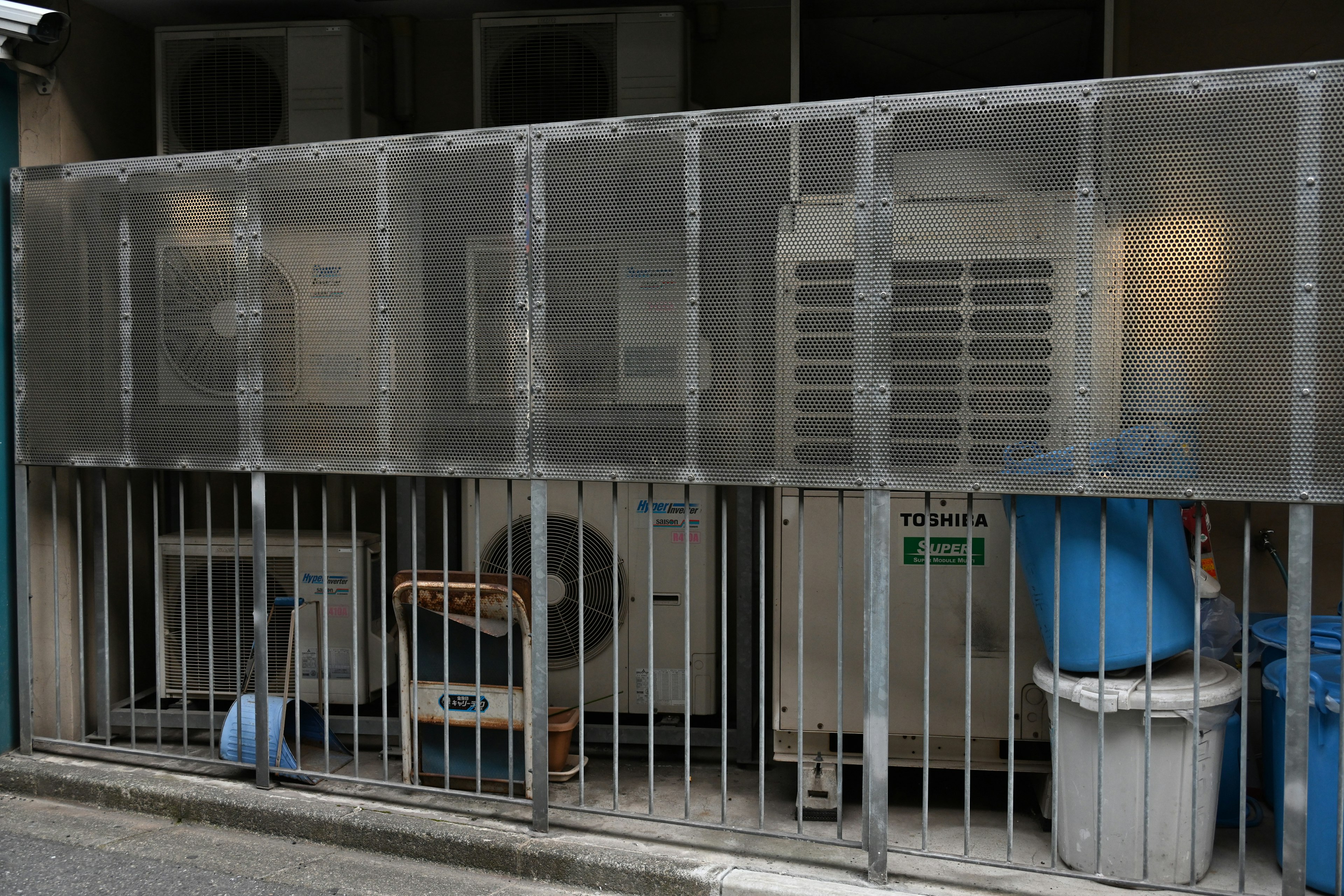 Outdoor area with transparent wall enclosing cooling units and metal fence