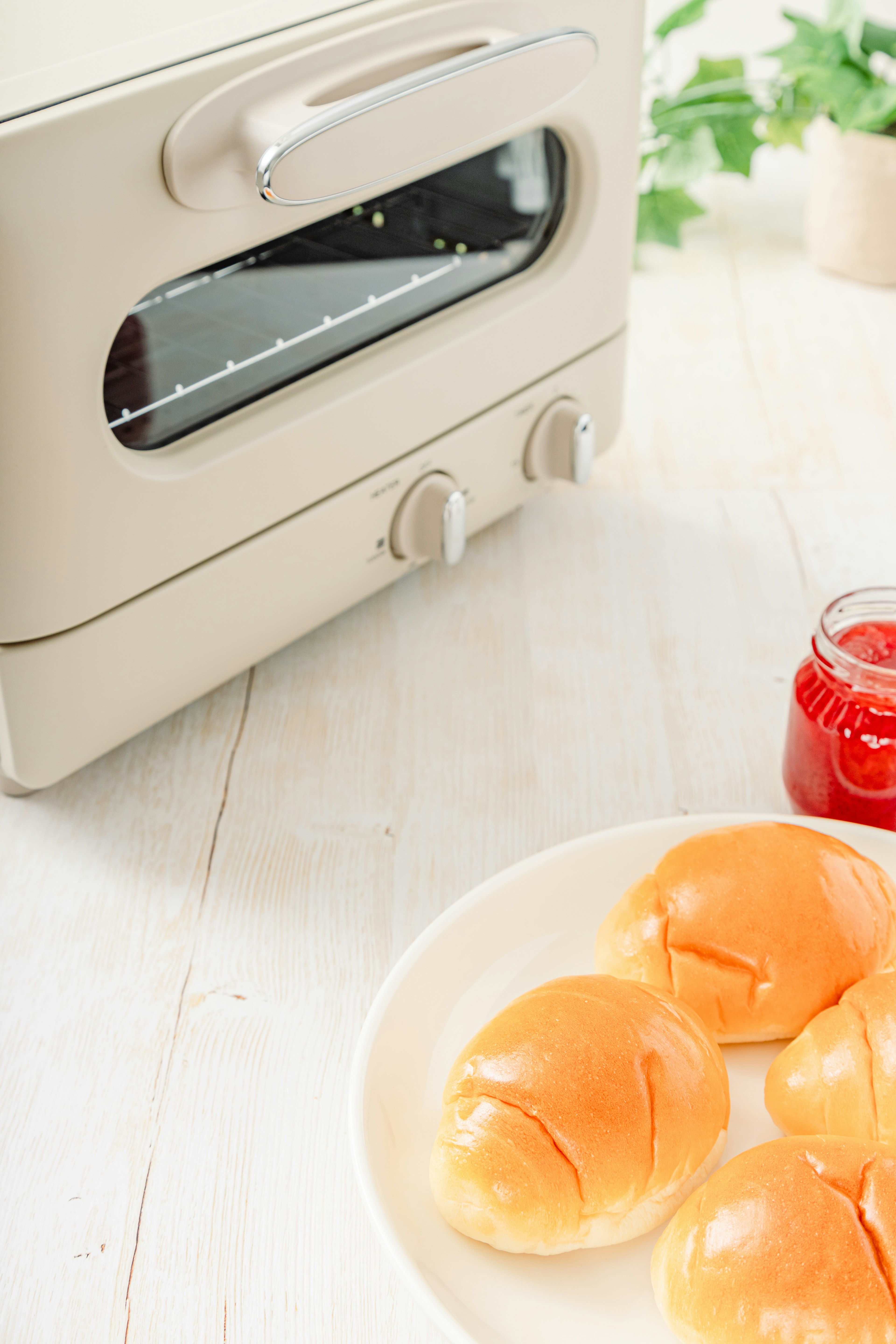 Toaster di atas meja putih dengan roti yang baru dipanggang