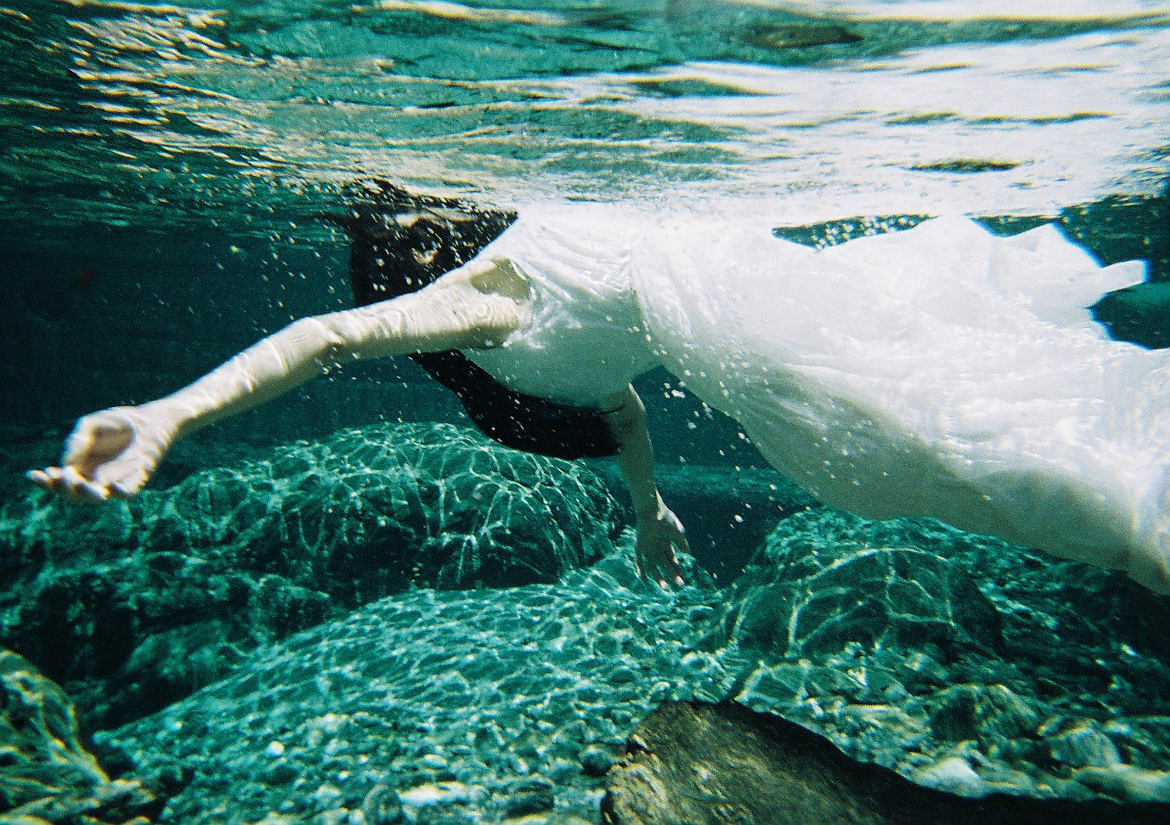 Mujer con vestido blanco nadando bajo el agua