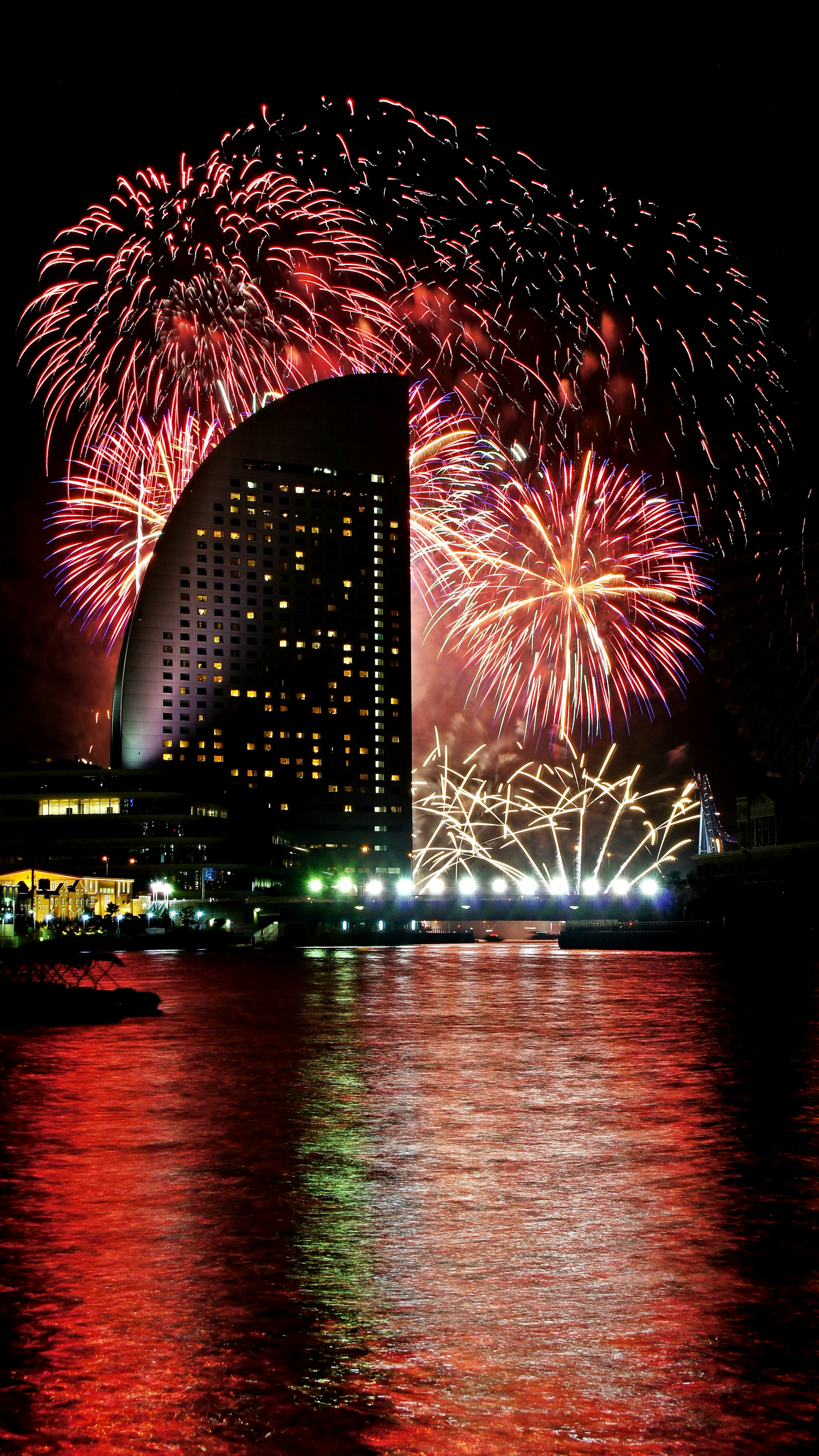 Orizzonte urbano con fuochi d'artificio nel cielo notturno e superficie d'acqua scintillante