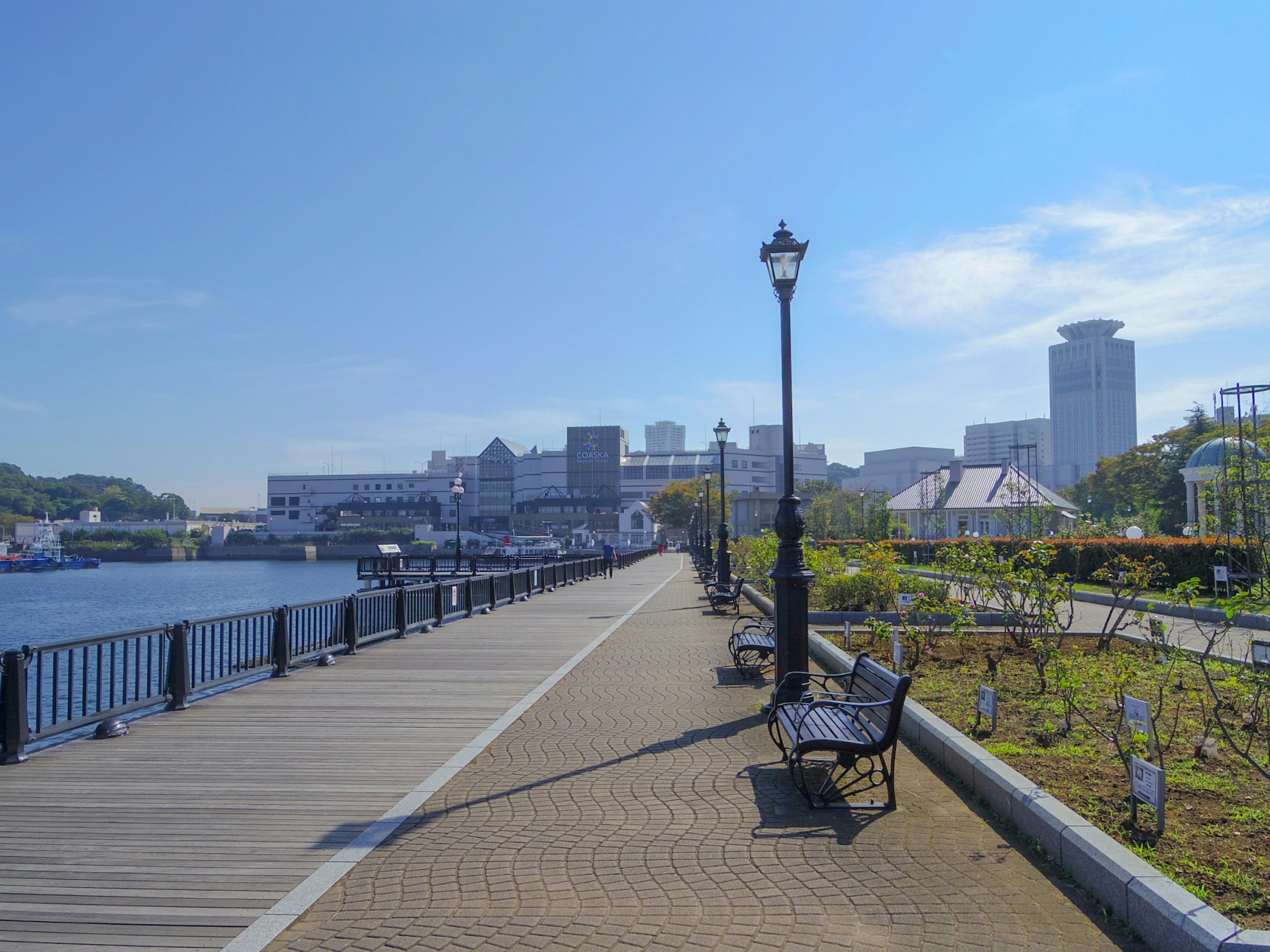 Scenic walkway along the river featuring benches and a street lamp