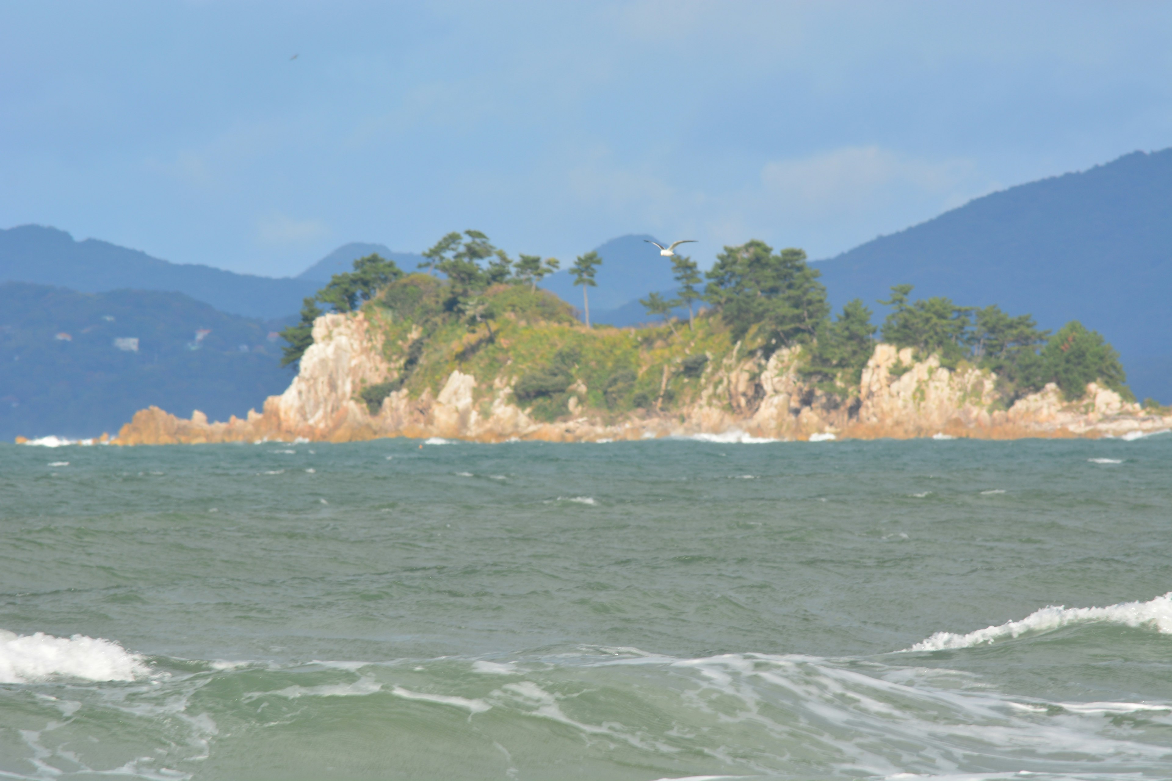 Petite île entourée d'eau avec des montagnes au loin