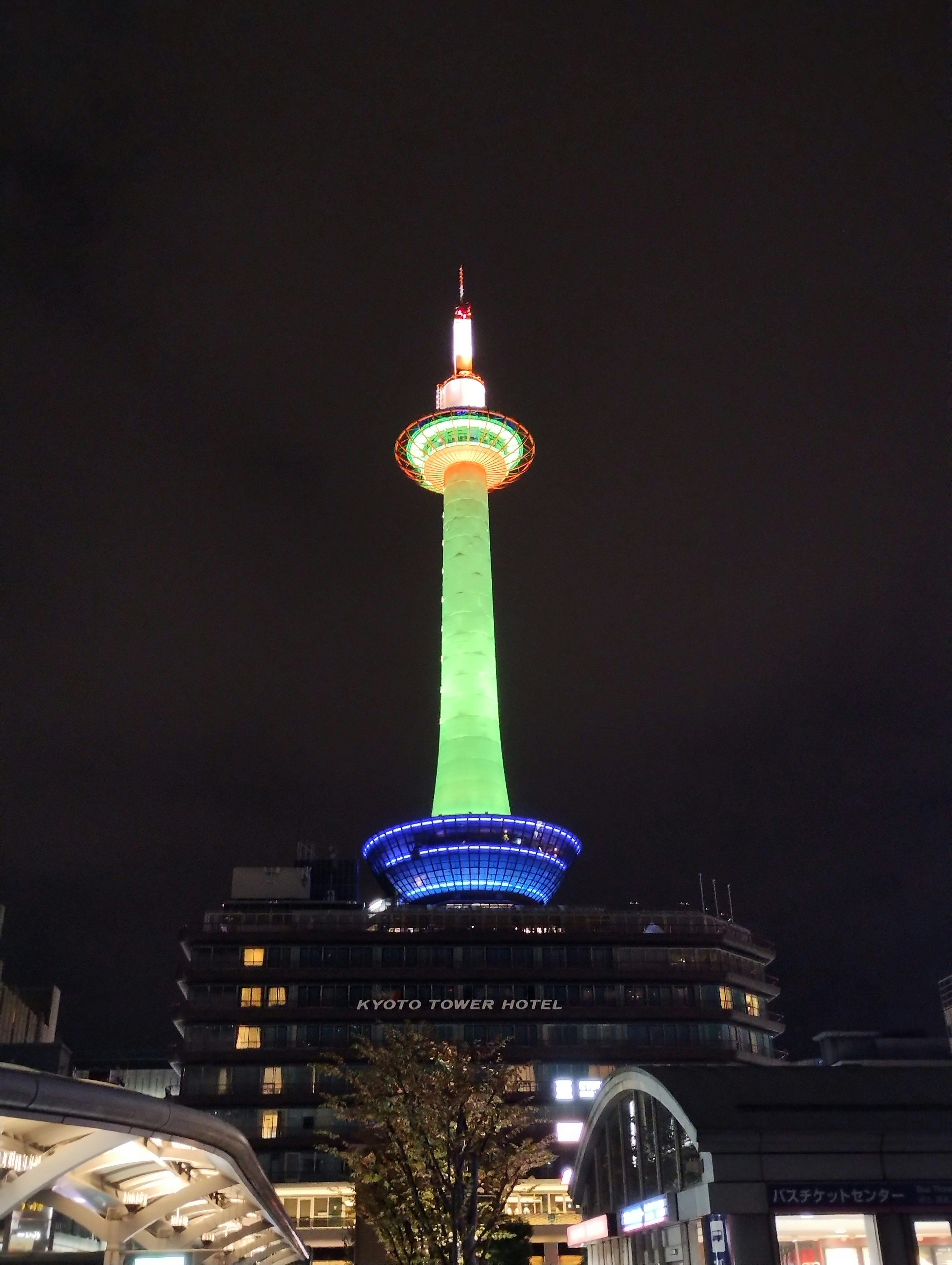 Kyoto Tower bei Nacht mit grünen und blauen Lichtern beleuchtet