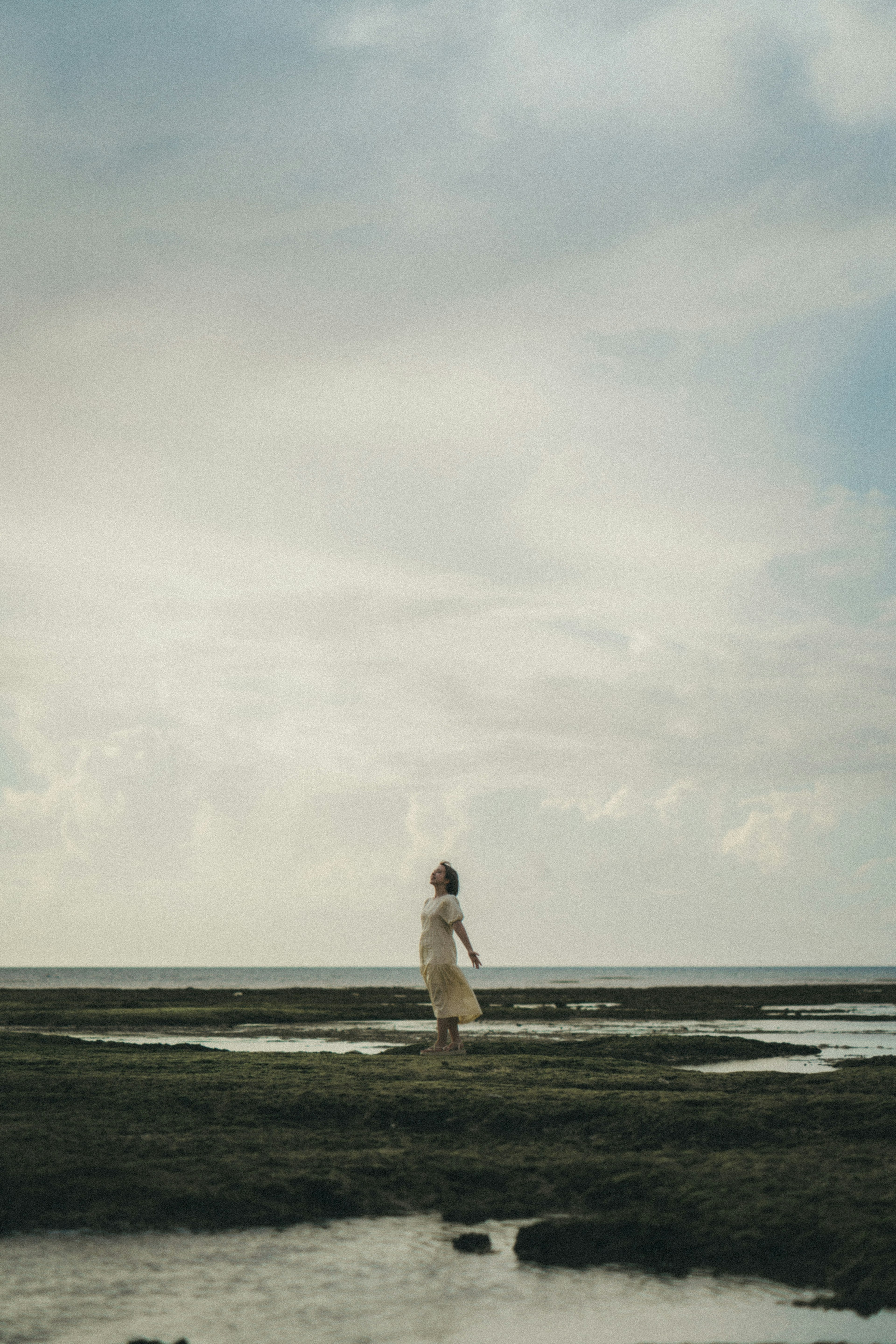 Una mujer con un vestido blanco de pie en una playa tranquila