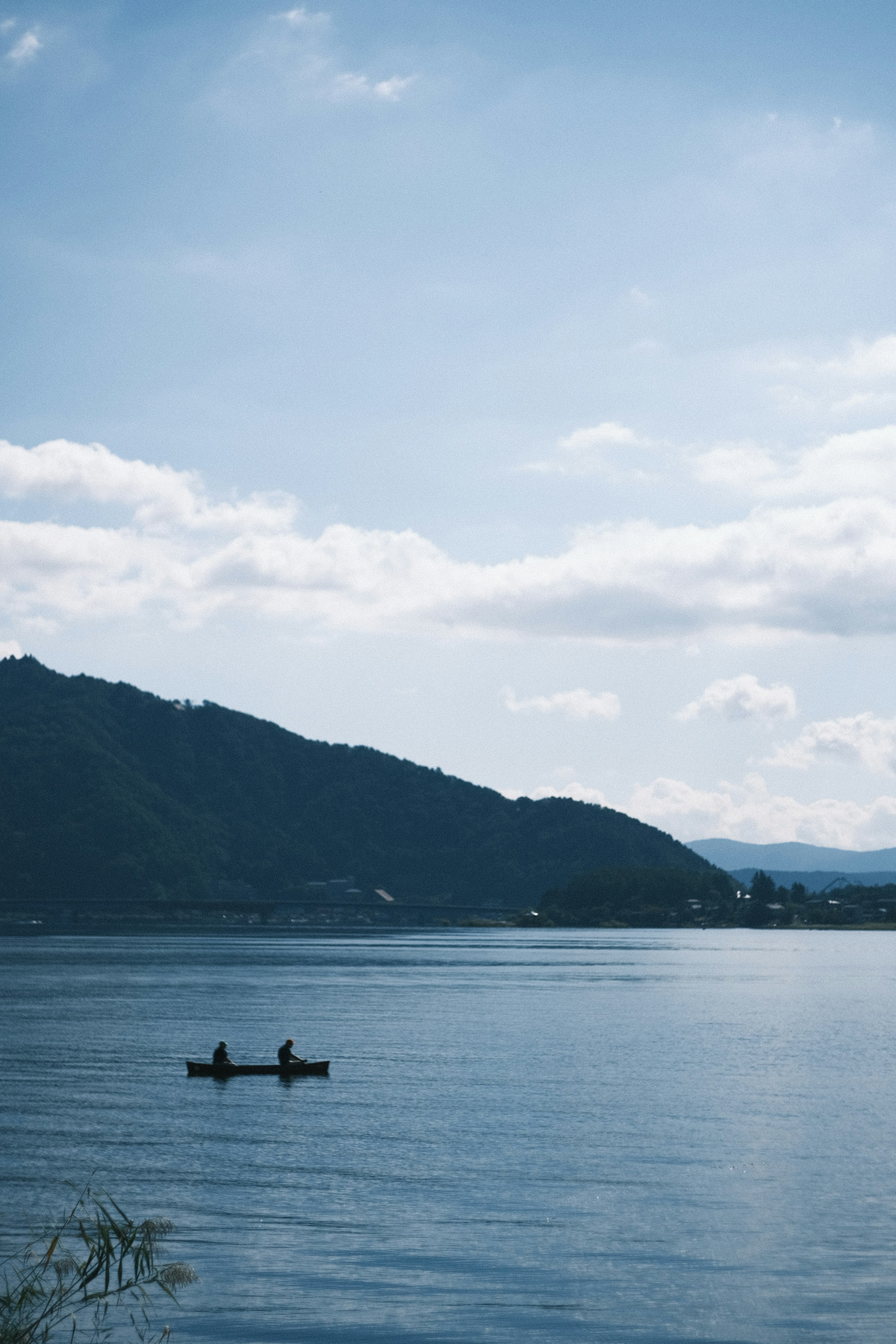 青い空の下でカヤックを漕ぐ二人の人々と穏やかな湖