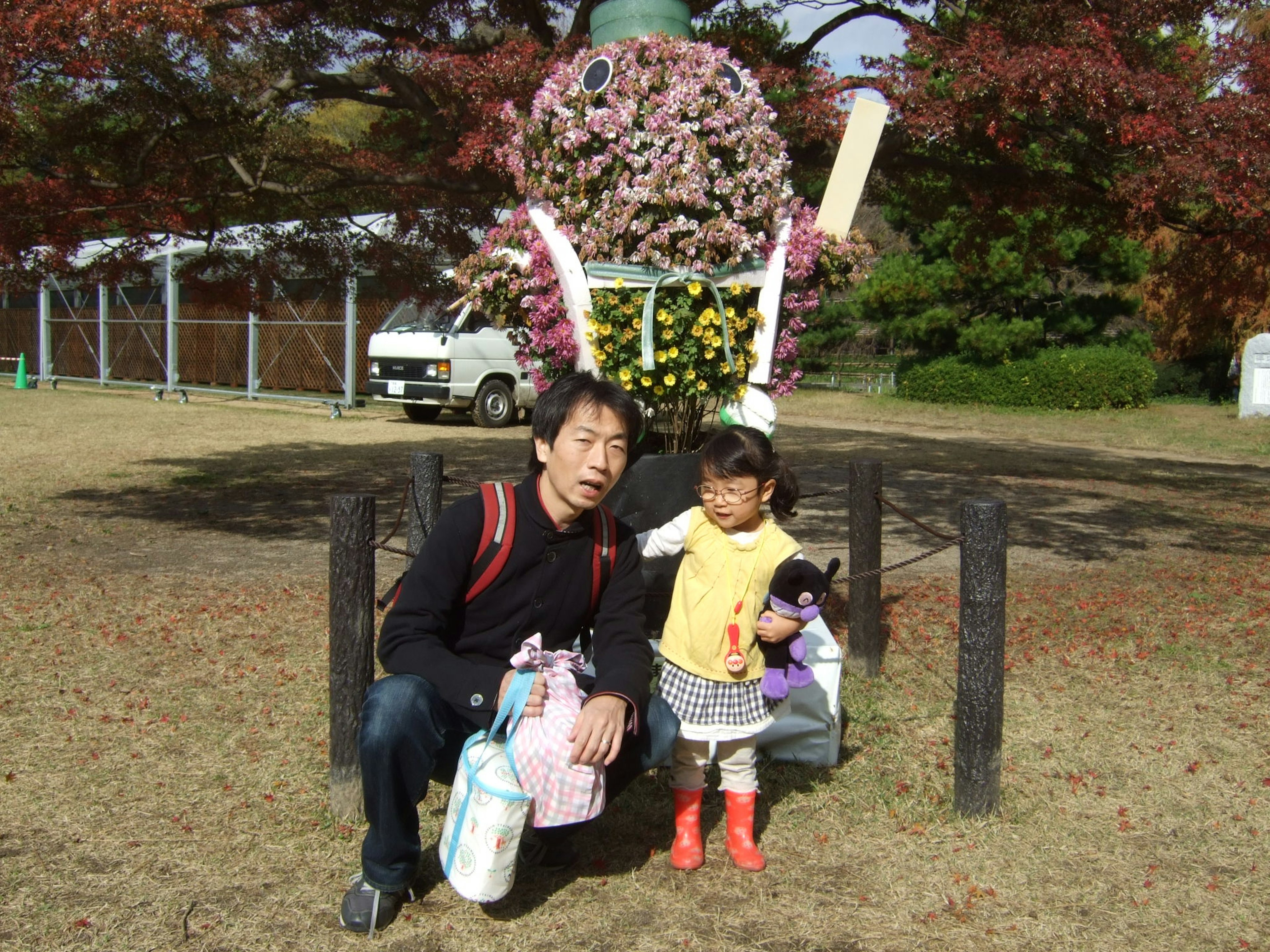 A man and a young girl standing in front of a flower decoration in a park