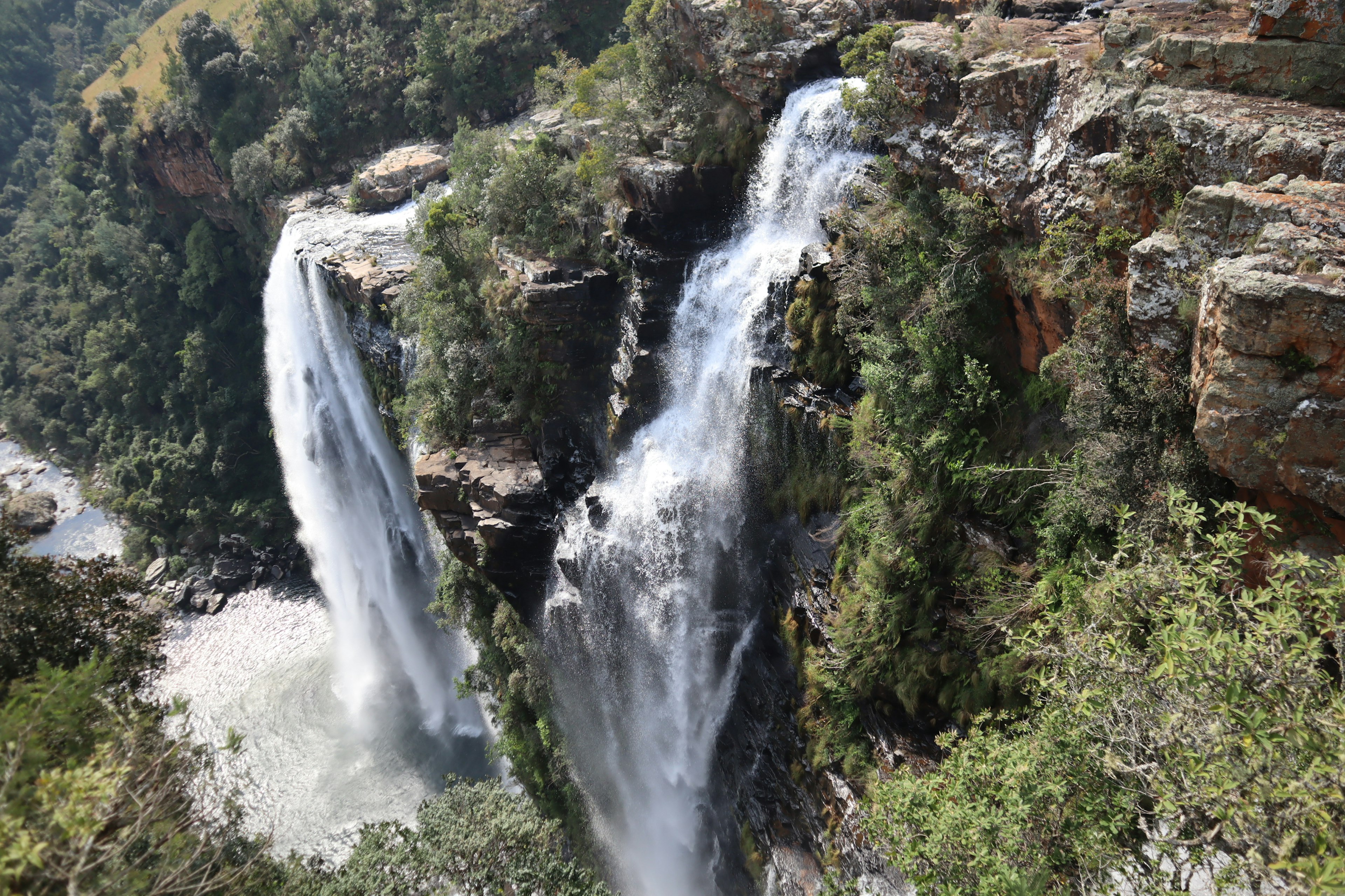 Pemandangan indah dua air terjun dikelilingi oleh pepohonan subur