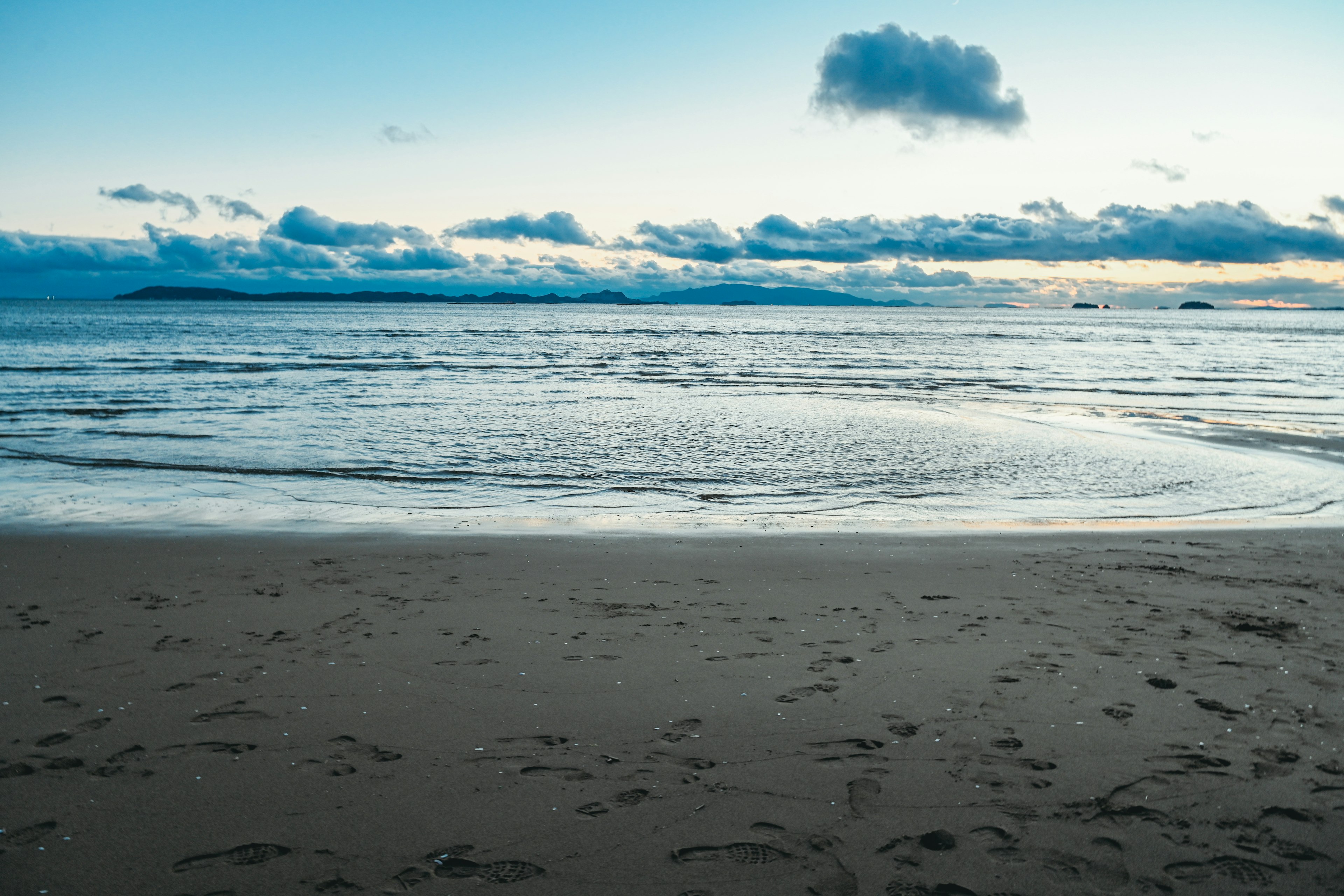 Pemandangan pantai tenang dengan air dan awan