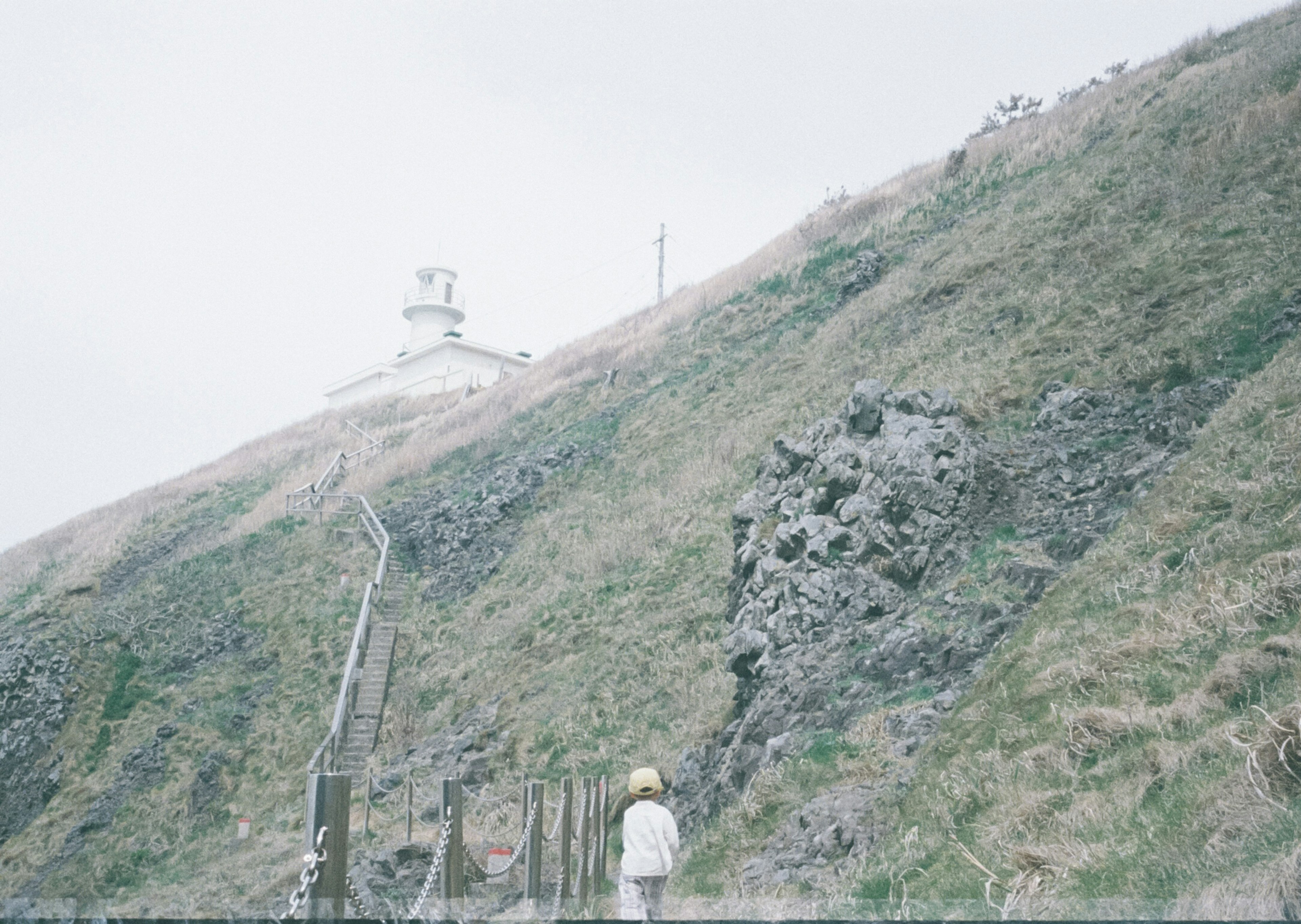 Collina nebbiosa con un faro e terreno roccioso