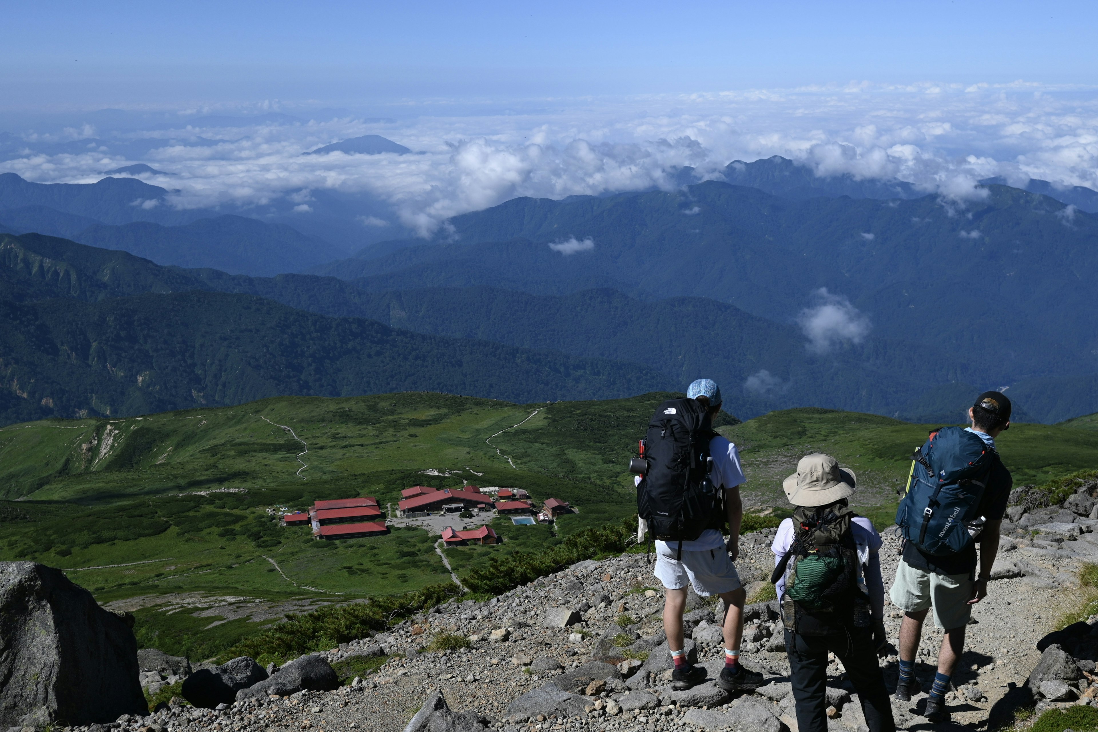 Randonneurs admirant une vue panoramique depuis le sommet d'une montagne avec des nuages et de la verdure