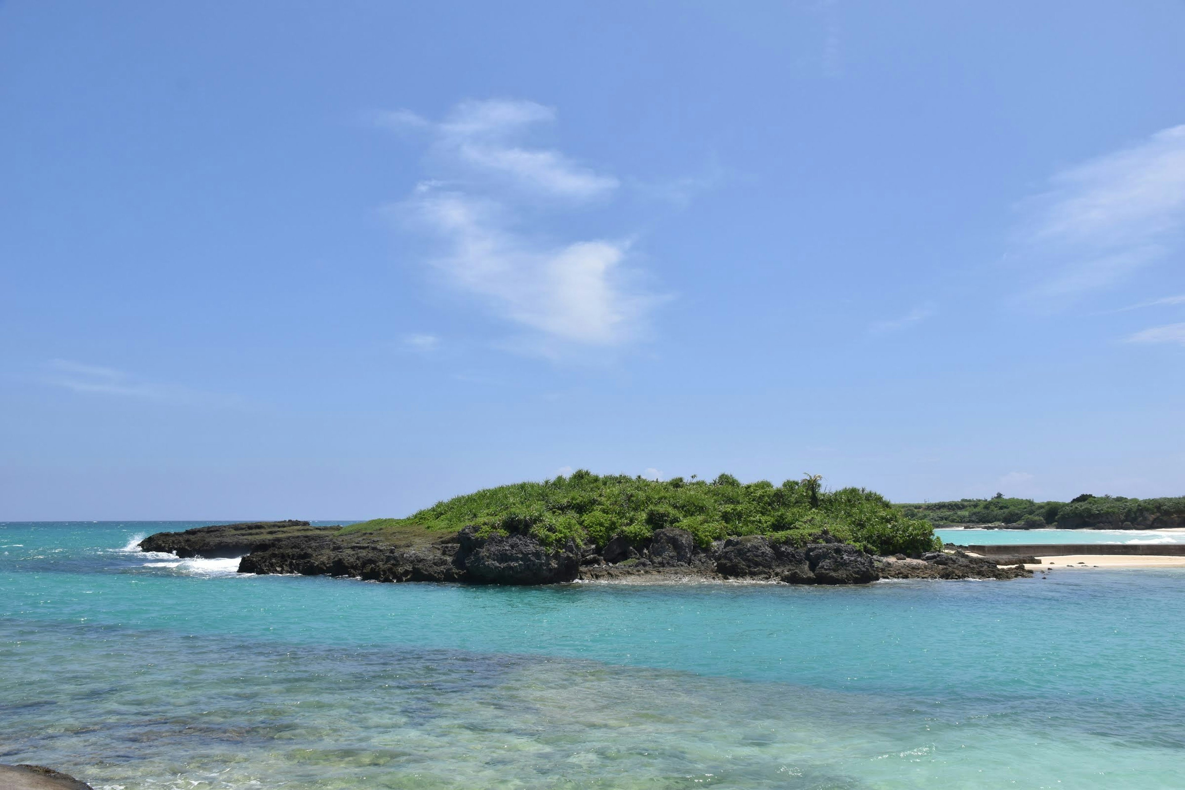 Un'isola verde lussureggiante circondata da acqua turchese e cielo blu chiaro