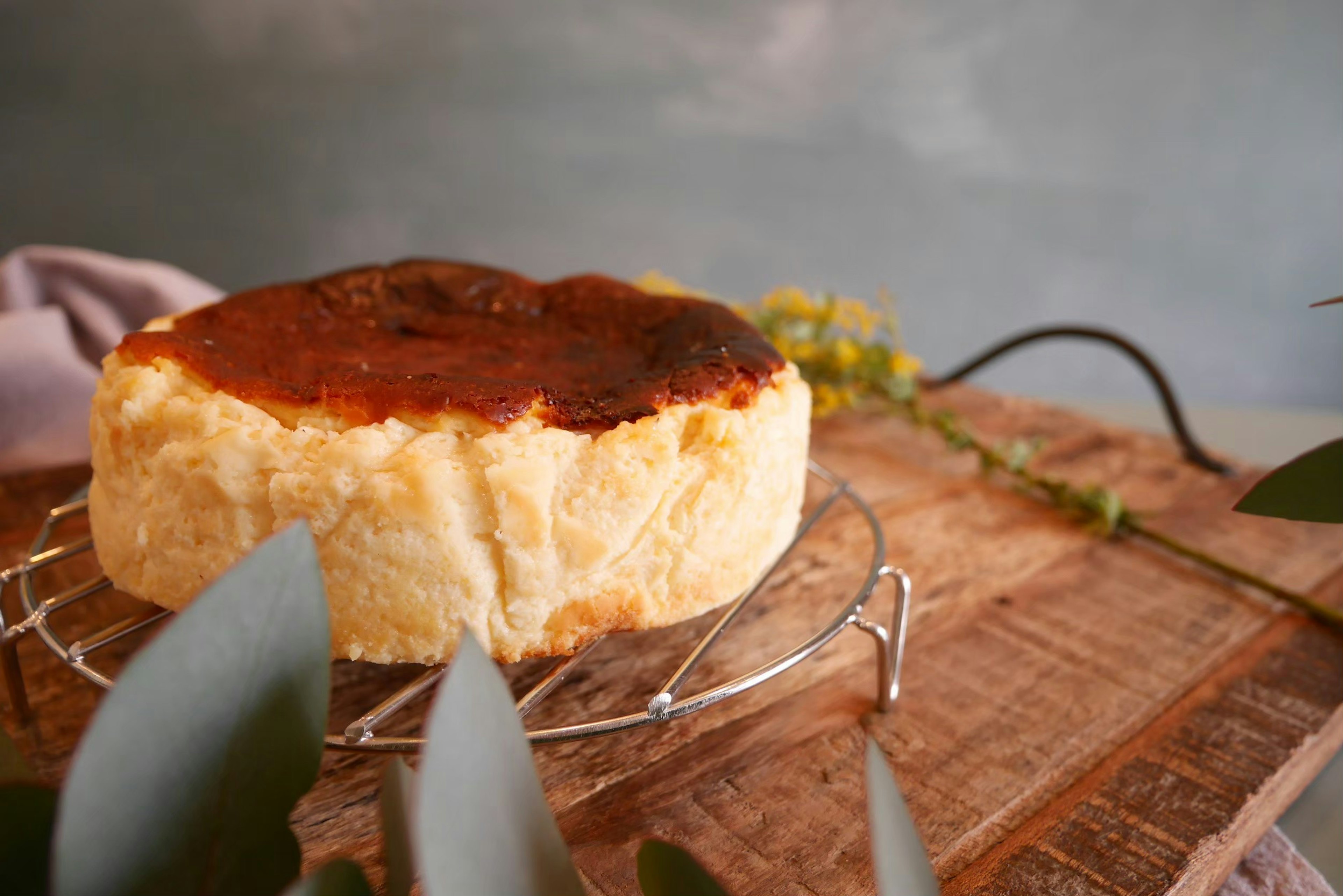 A baked cheesecake with a golden crust on a wire rack