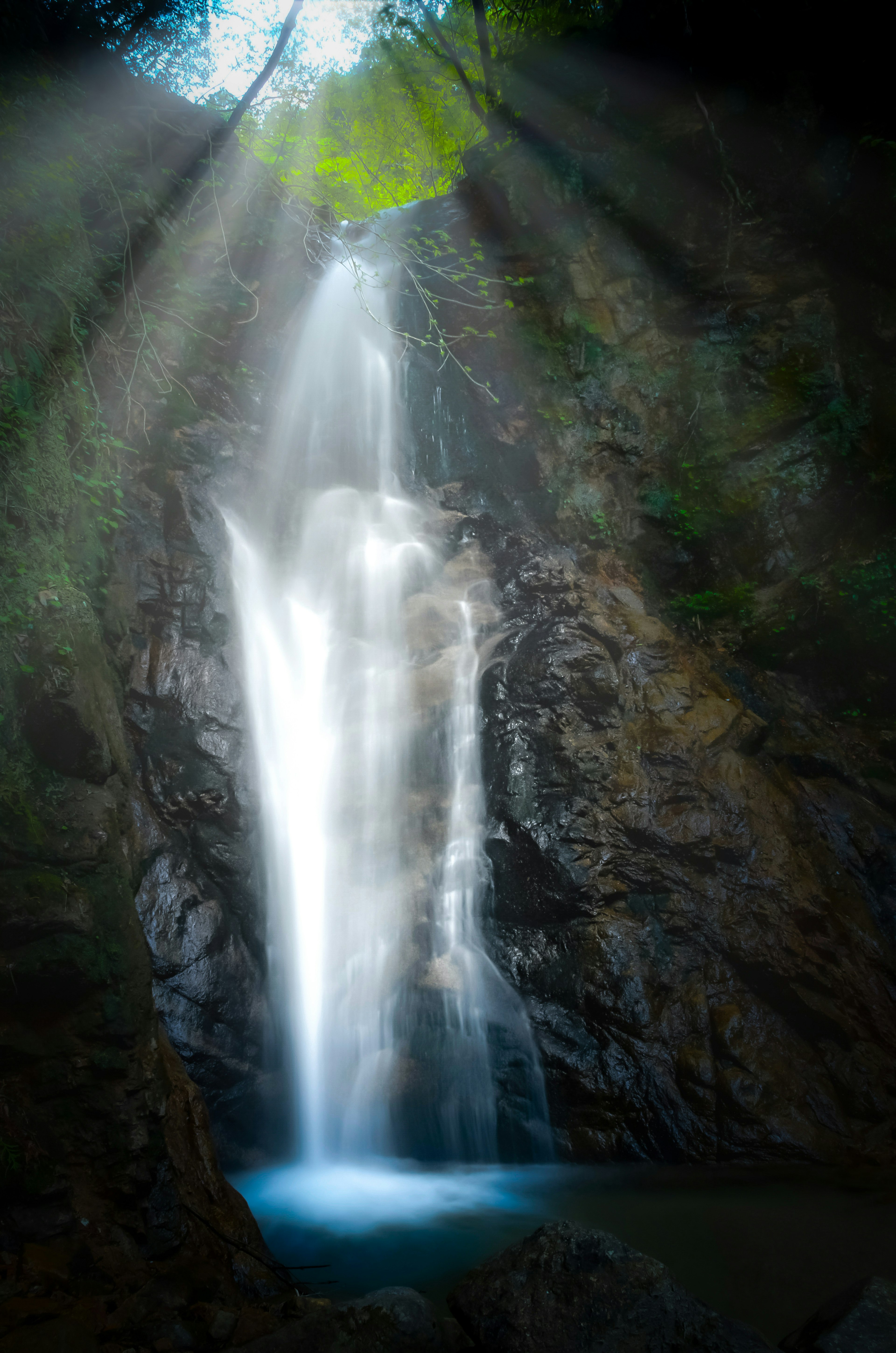 A beautiful waterfall cascading down rocks with sunlight streaming through creating a magical atmosphere