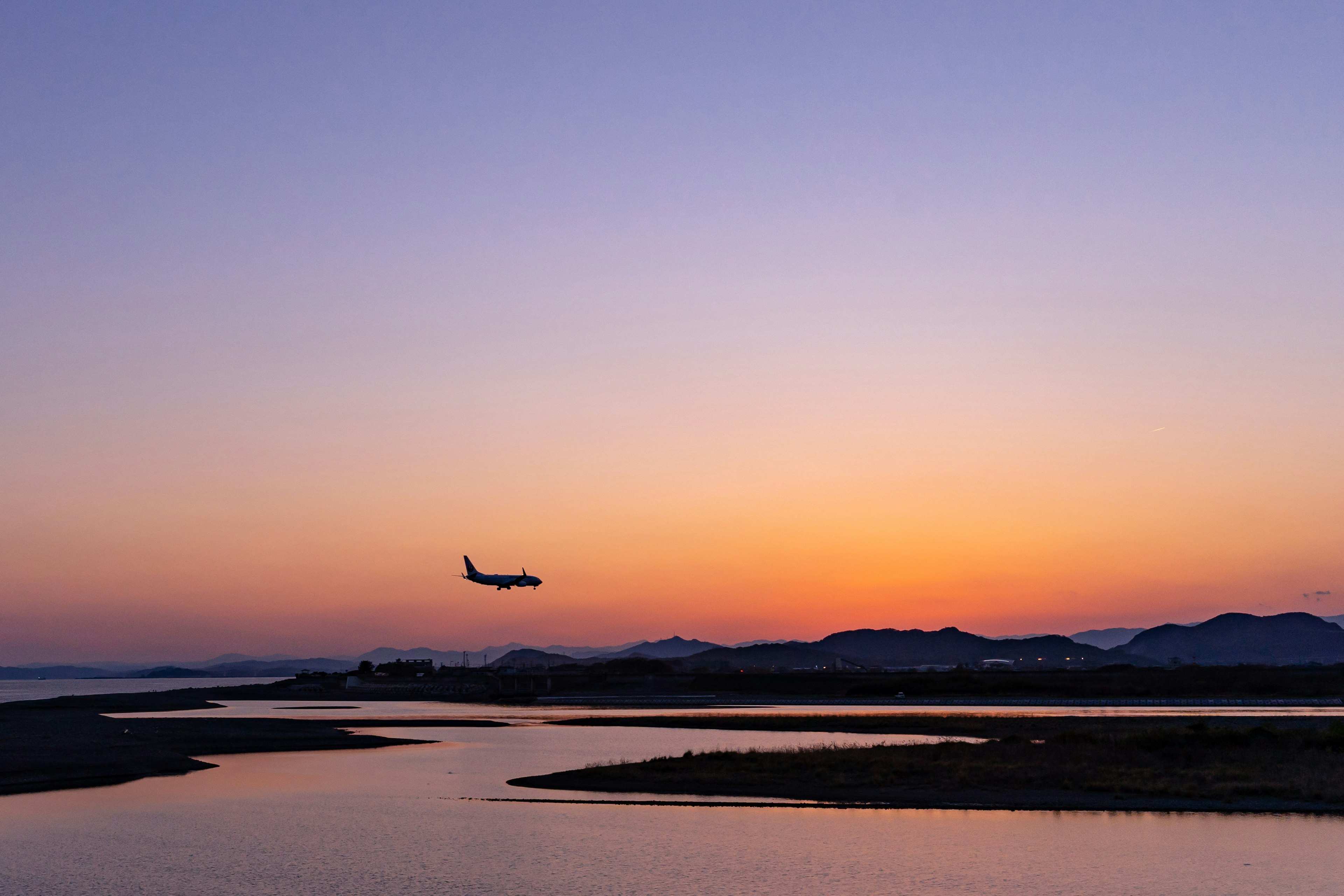 Un avión aterrizando contra un cielo de atardecer